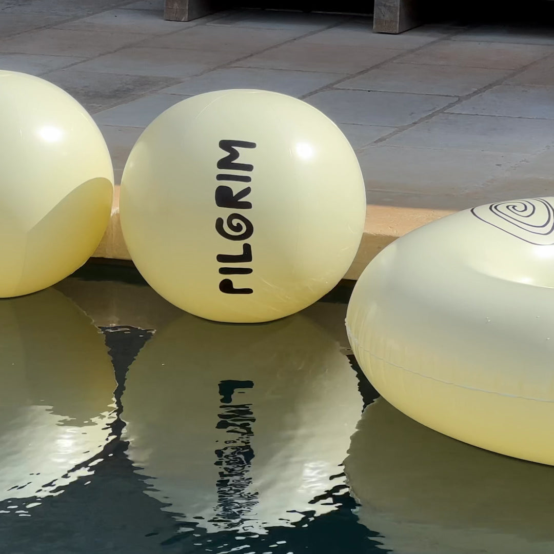 A collection of white inflatable balls featuring black symbols floating in a pool, embodying a blend of trendy design and Scandinavian minimalism.