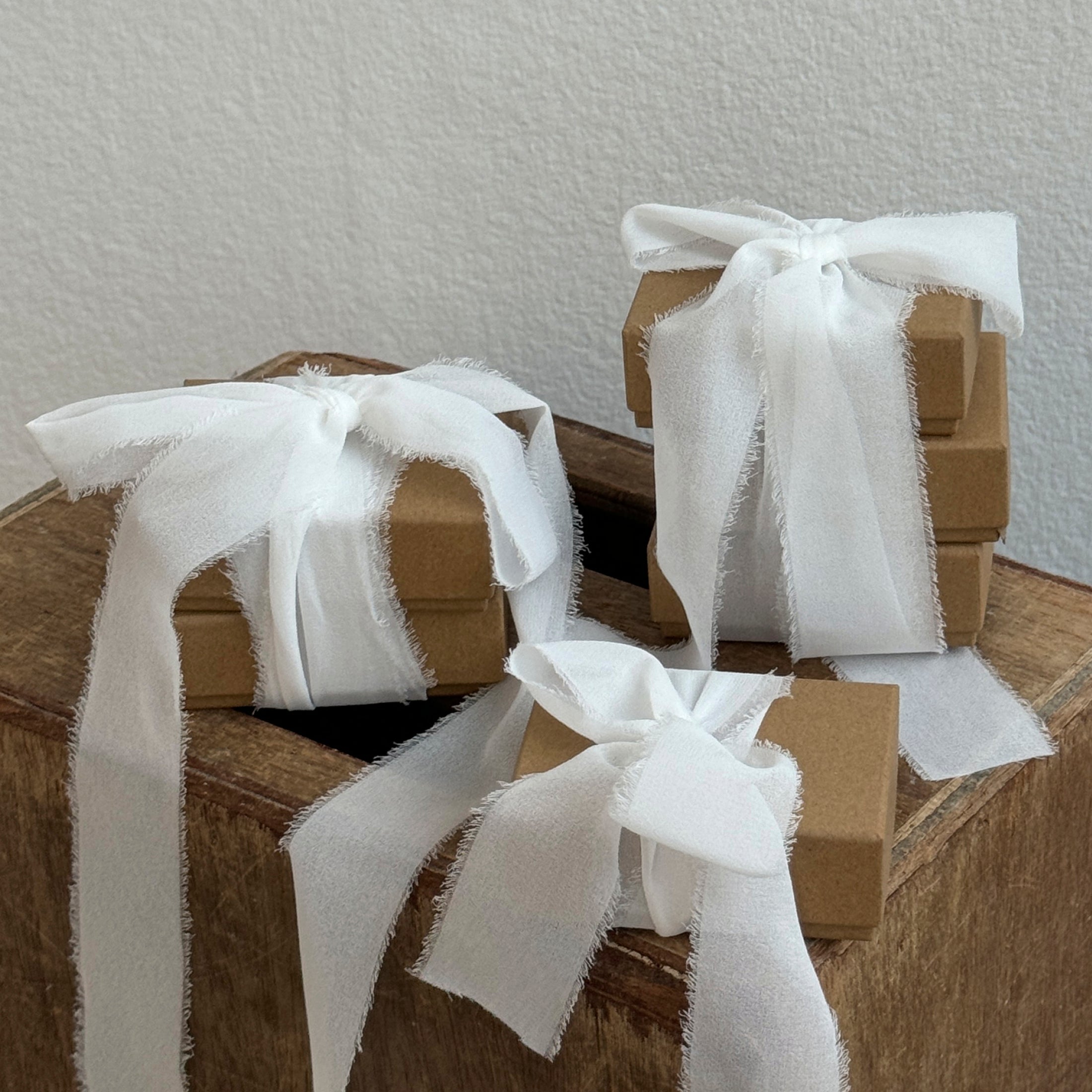 A collection of brown boxes adorned with elegant white ribbons, suggesting thoughtful, handcrafted packaging, reflecting Pilgrim's inclusive and stylish Scandinavian jewelry brand.