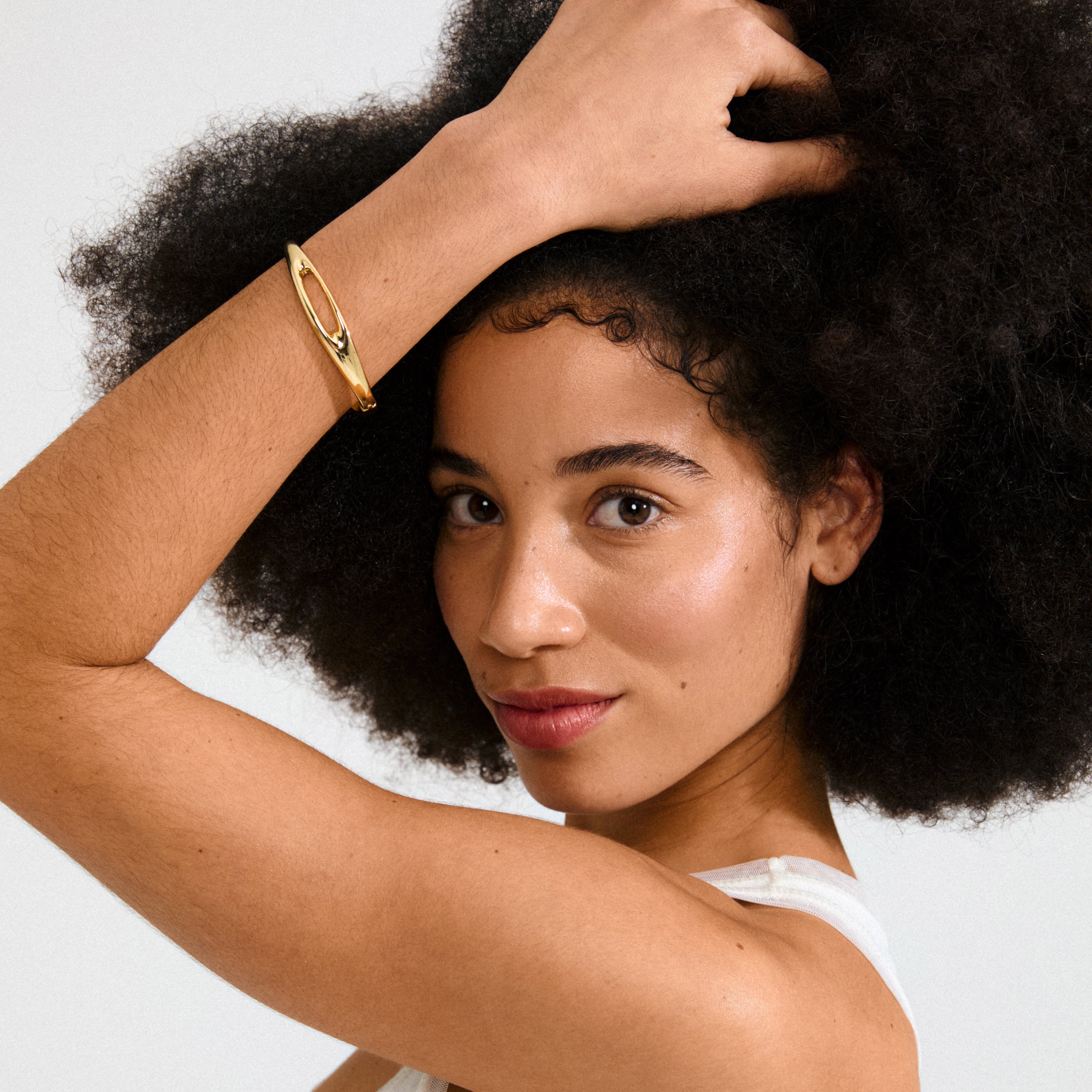 Young woman wearing Pilgrim's gold-plated FREE bangle with a cut-out design, showcasing a minimalist and confident style.