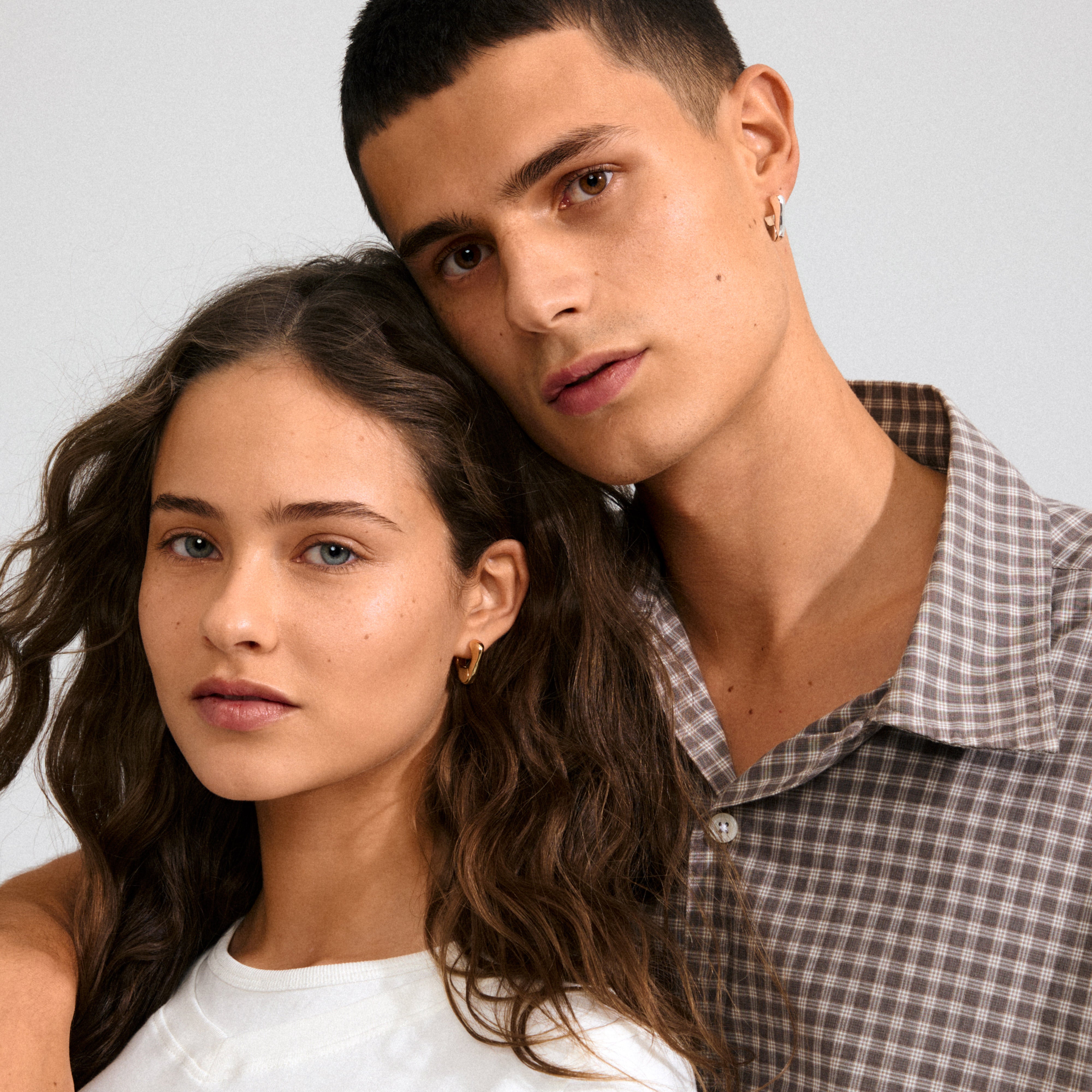 Two young adults showcasing Pilgrim's FREE earrings silver-plated, highlighting the elegant, sculptural design and everyday style of these essential accessories.