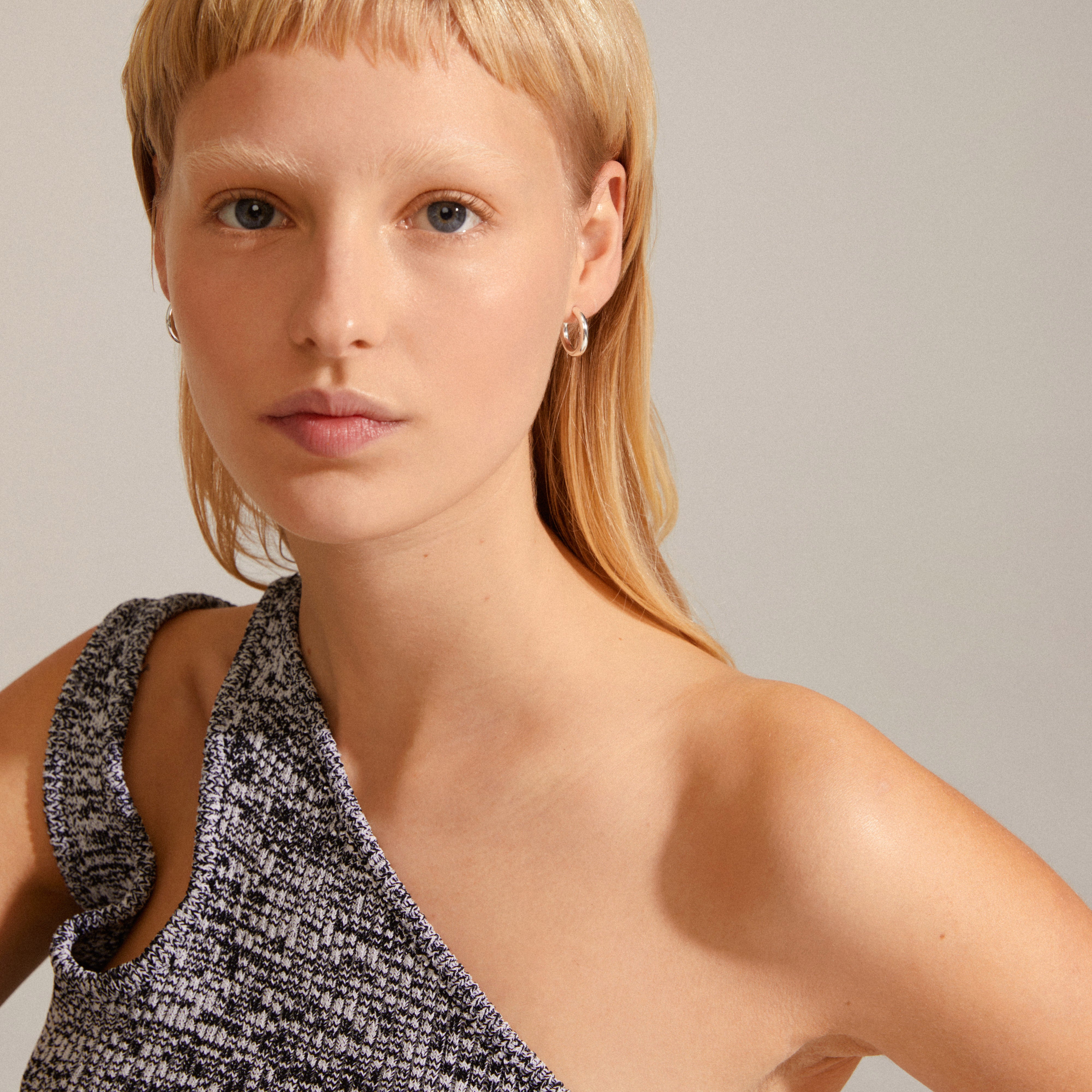 DOLAG earrings in silver-plated finish, showcased by a blonde woman wearing a black and white dress. These chunky hoops offer versatile, stylish accessorizing.