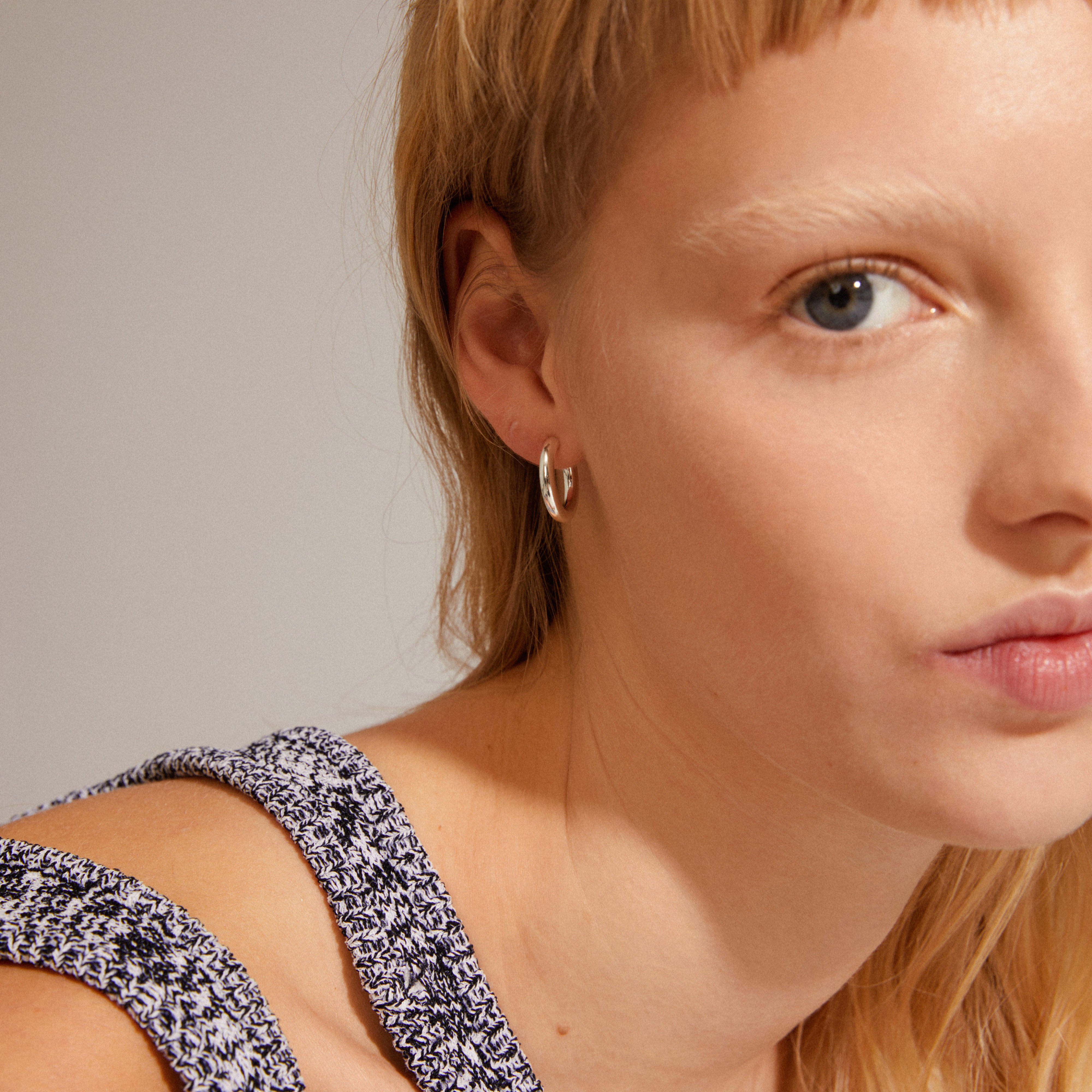 DOLAG earrings silver-plated, showcased in a close-up of a woman wearing them, highlighting their chunky, shiny finish suitable for mixing and matching.