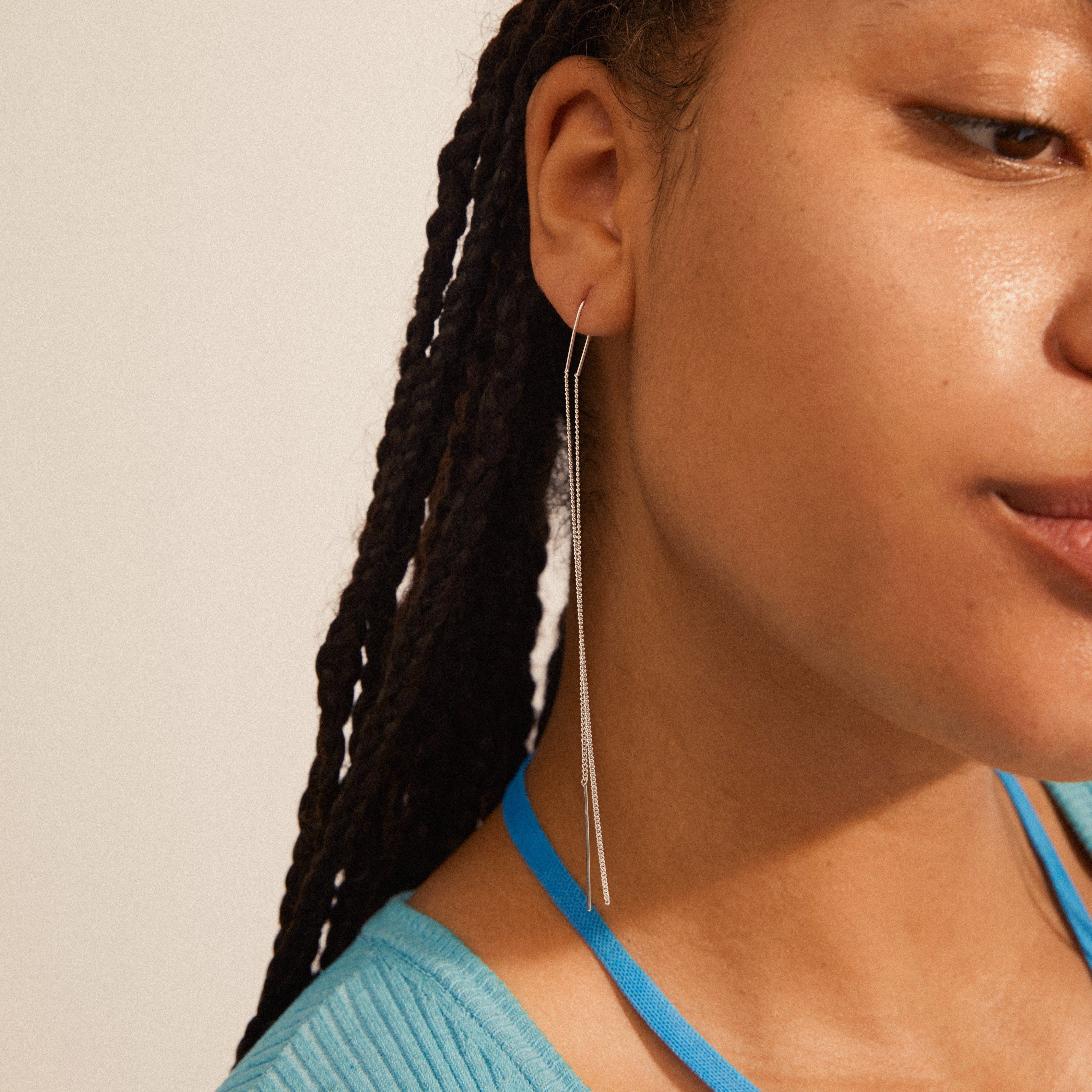 Close-up of a woman's ear adorned with Pilgrim's ENCHANTMENT silver-plated chain earrings, featuring elongated, minimalist design from the Enchantment collection.