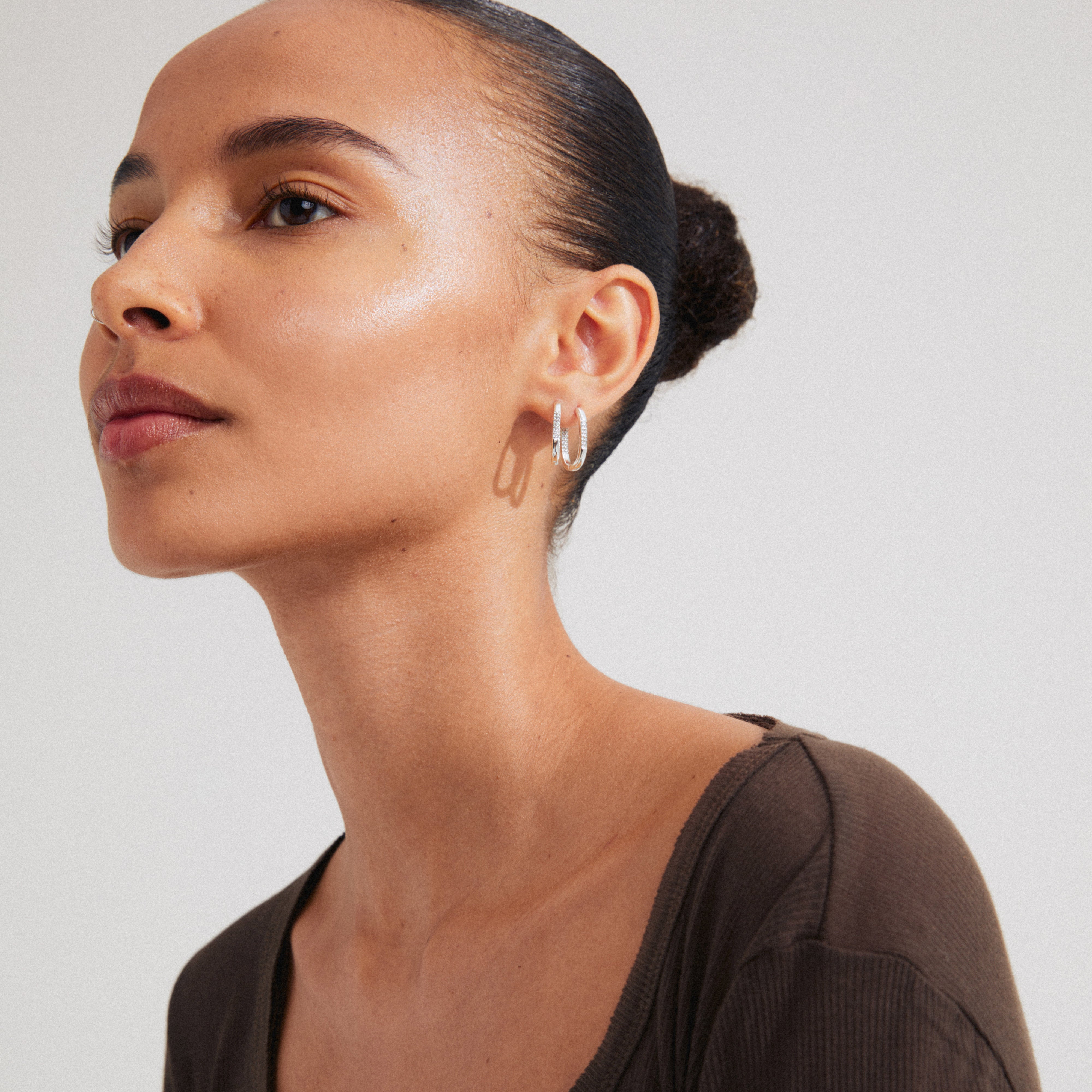 A woman wearing Pilgrim's STAR hoops, silver-plated earrings, featuring a shiny finish with sparkling Preciosa crystals and a convenient click clasp.