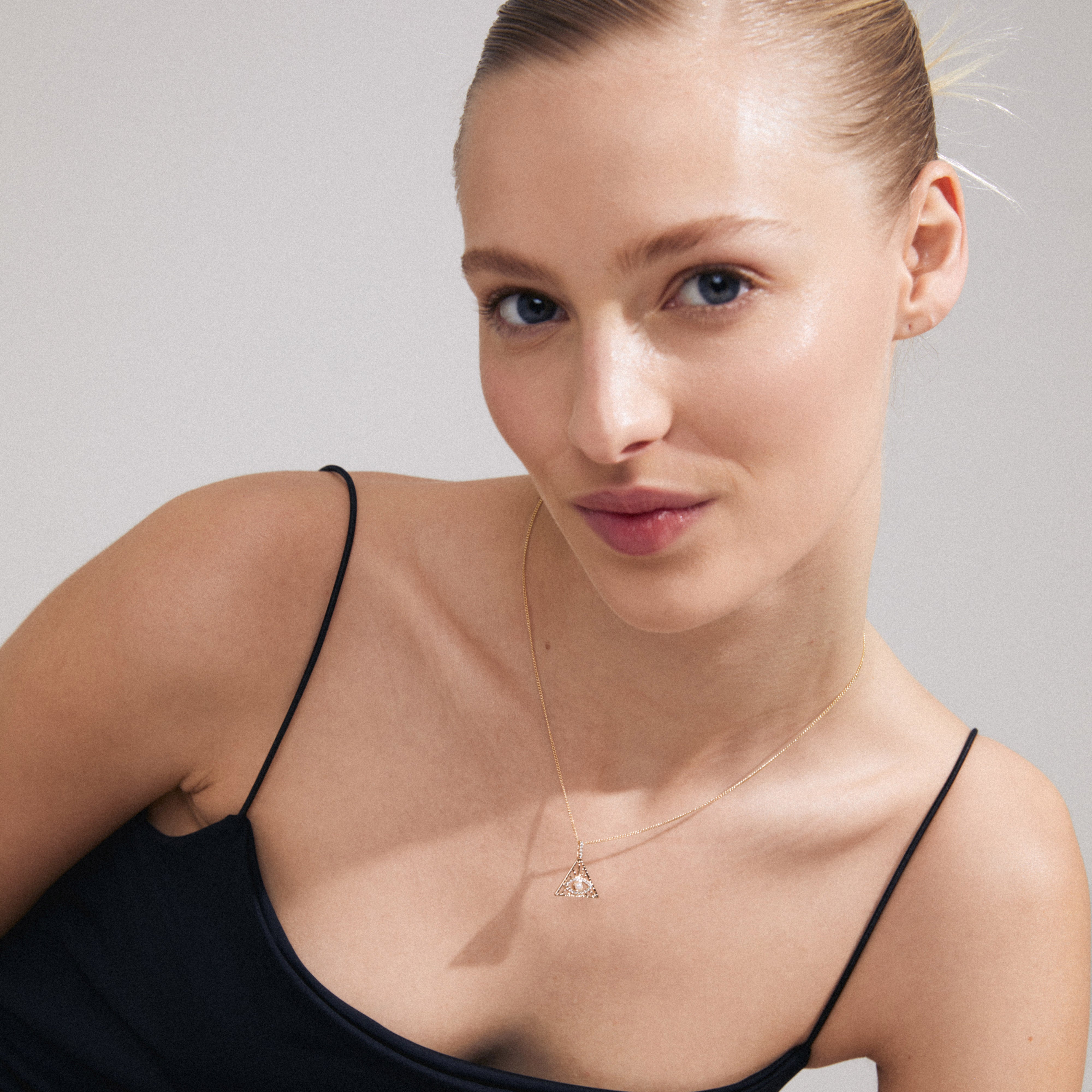 FOCUS necklace gold-plated with triangular pendant and sparkling crystals, worn by a woman, symbolizing focus and luxury bohemian style.