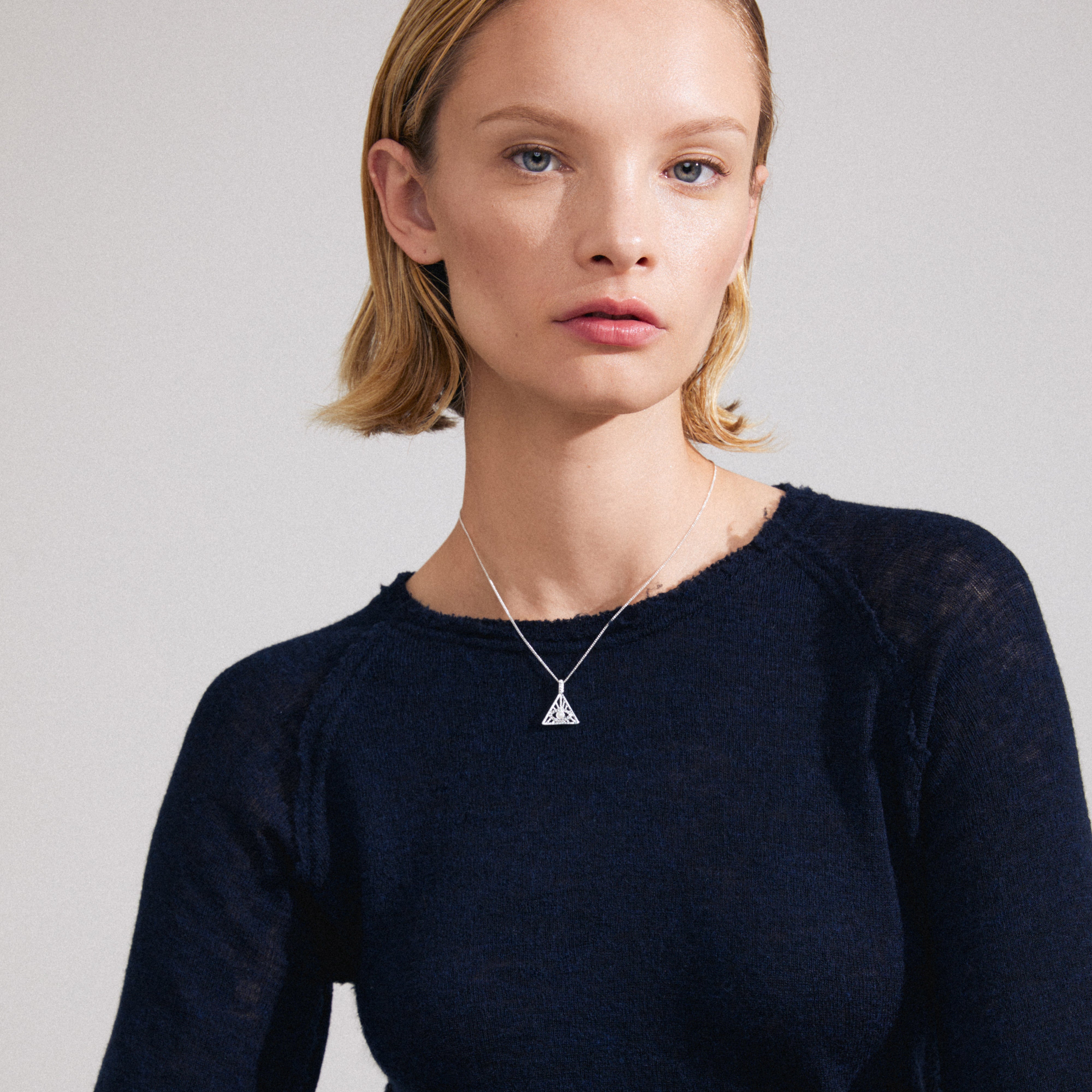 FOCUS necklace silver-plated on woman's neck, featuring a triangular pendant with Preciosa crystals, symbolizing the all-seeing eye and luxury bohemian style.