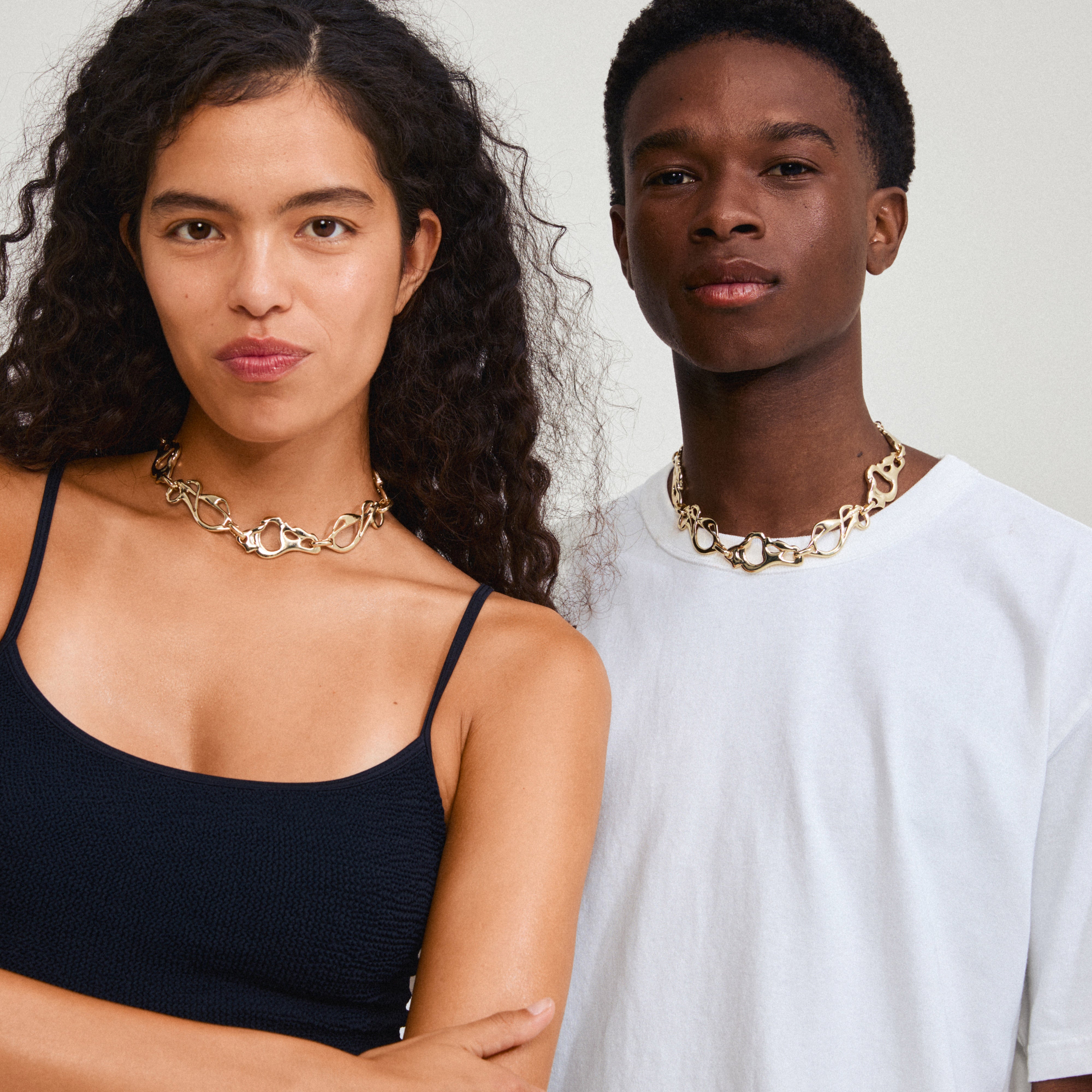 STARLIGHT necklace gold-plated on a woman with curly hair, showcasing its abstract, interconnected links for a stylish and elegant look.