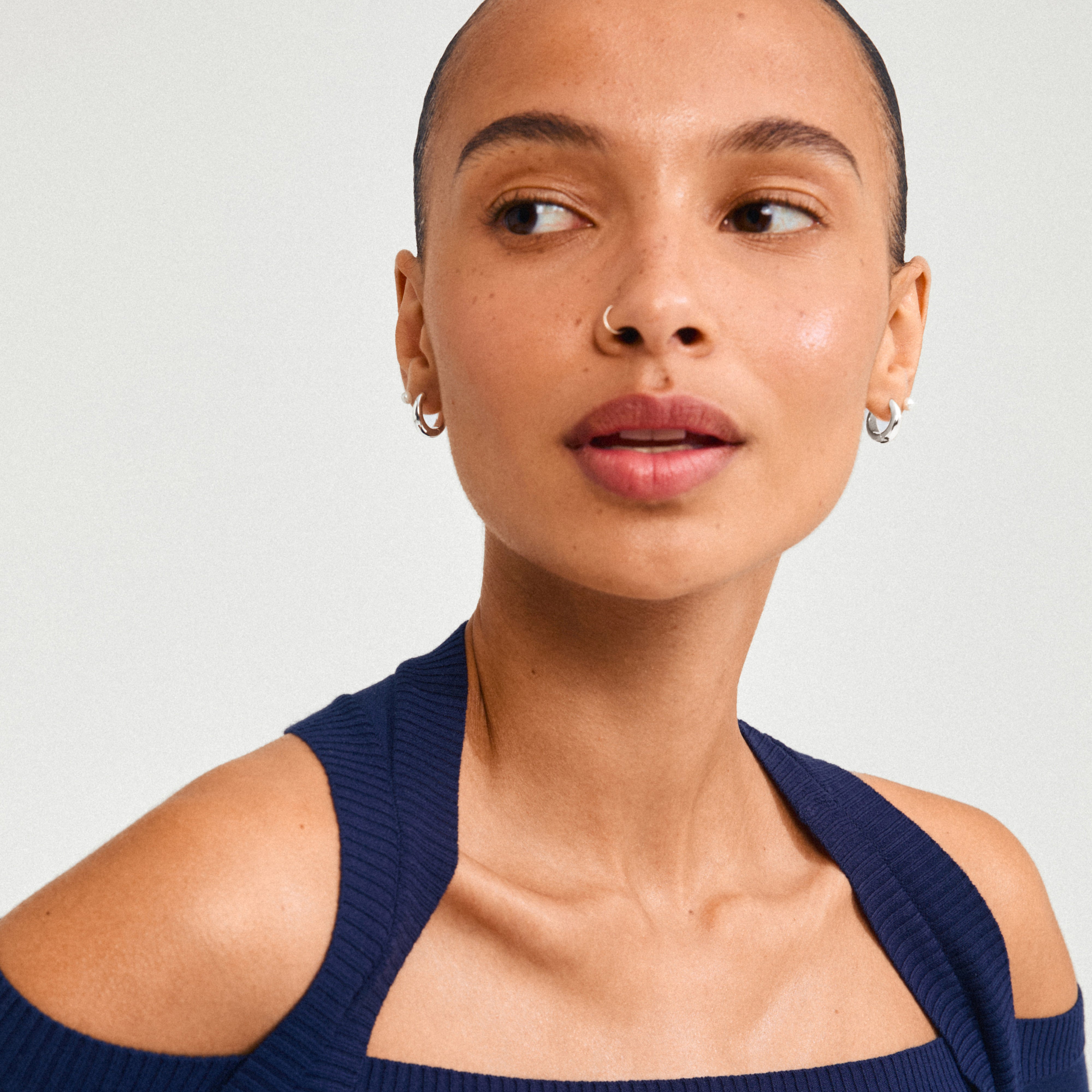 Woman wearing Pilgrim's STARLIGHT earrings, featuring a 2-in-1 set with freshwater pearl studs and silver-plated chunky huggie hoops, highlighting Scandinavian craftsmanship.