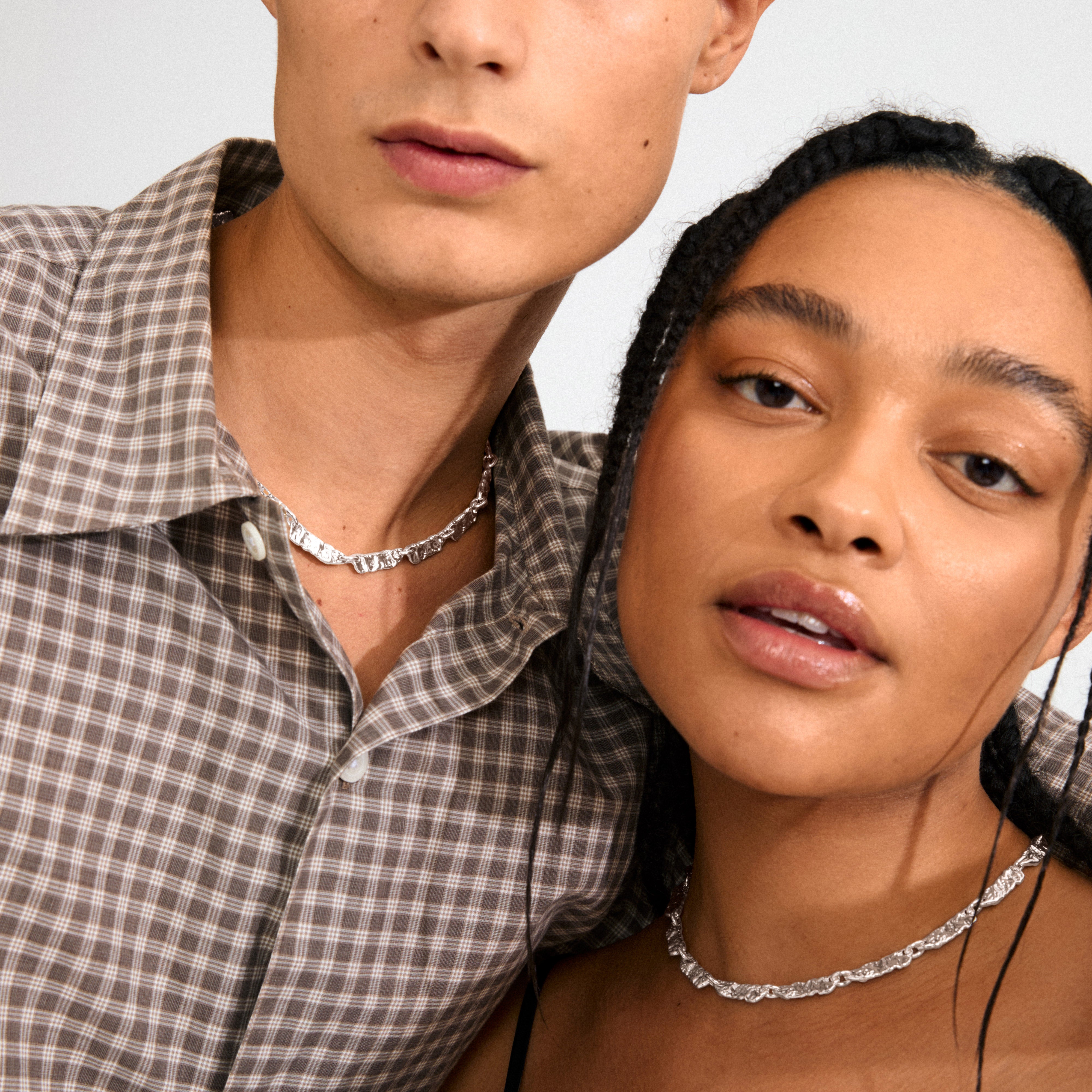 Models showcase Pilgrim's INSTANT necklace, a silver-plated choker with crumpled, textured links, radiating a handcrafted, stylish vibe.