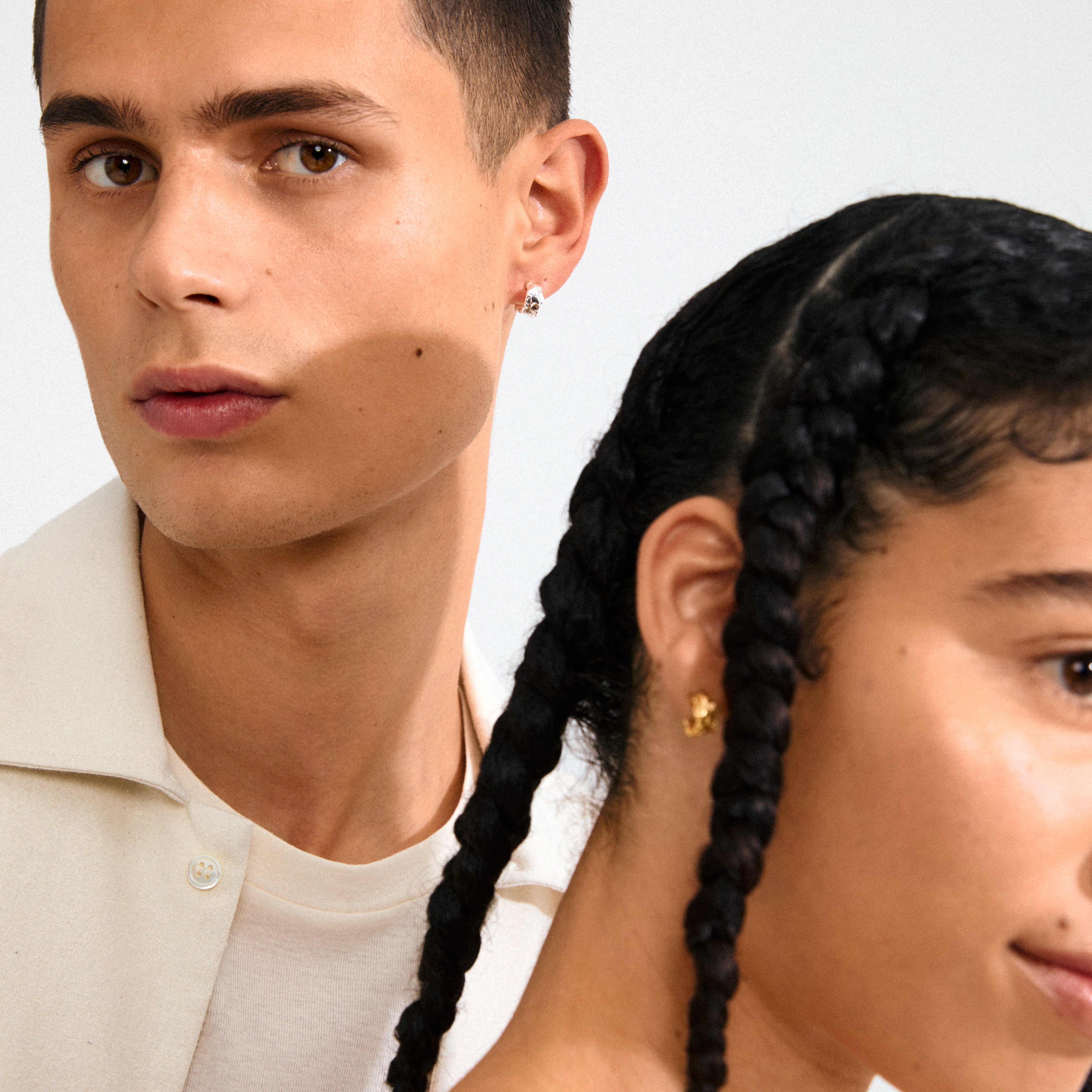 Two models showcase the INSTANT earrings: a silver hoop on the left model and a gold earring on the right, highlighting Pilgrim's blend of elegance and style.