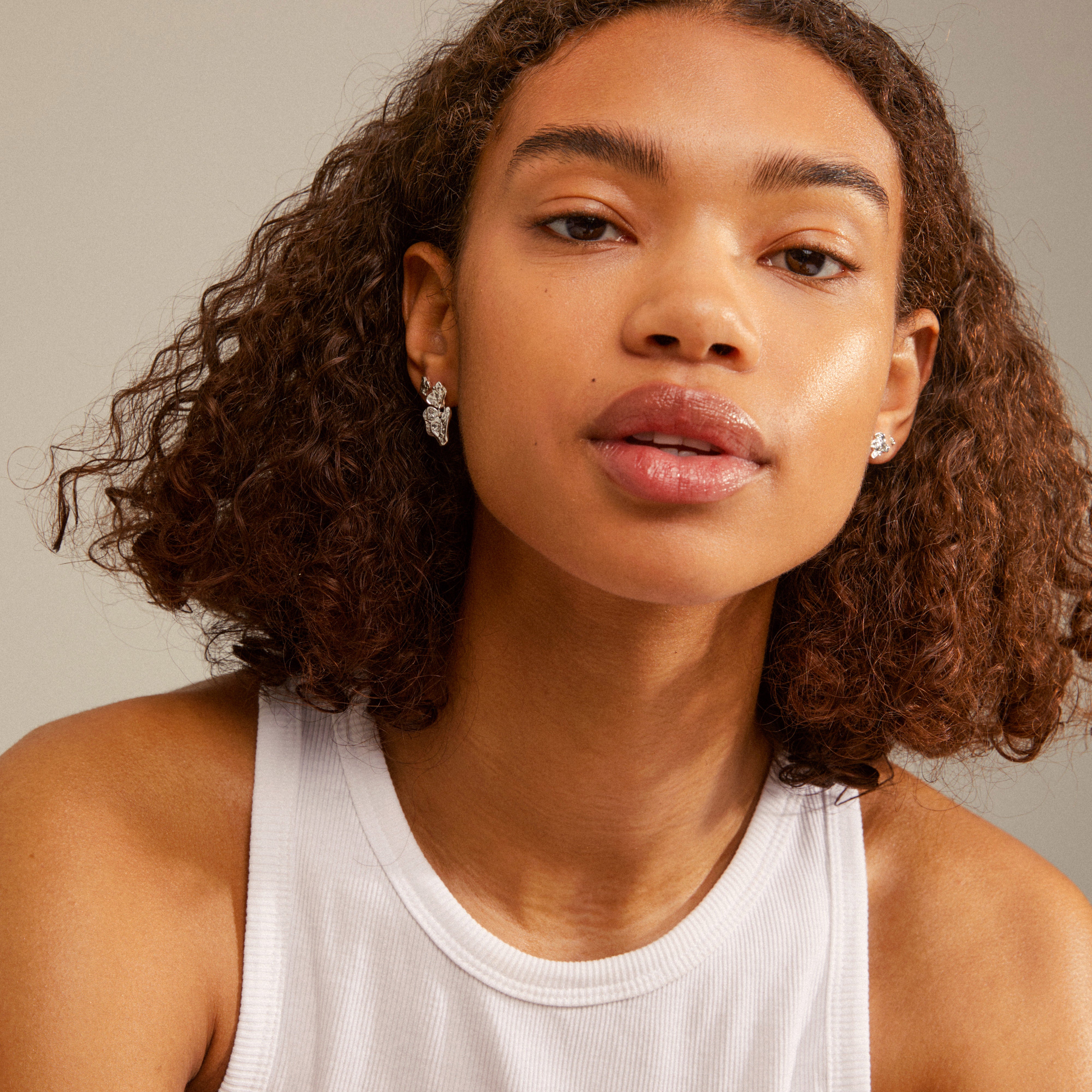Woman with curly hair wearing HORIZON earrings silver plated, showcasing versatile ear styling options from Pilgrim's trendy collection.