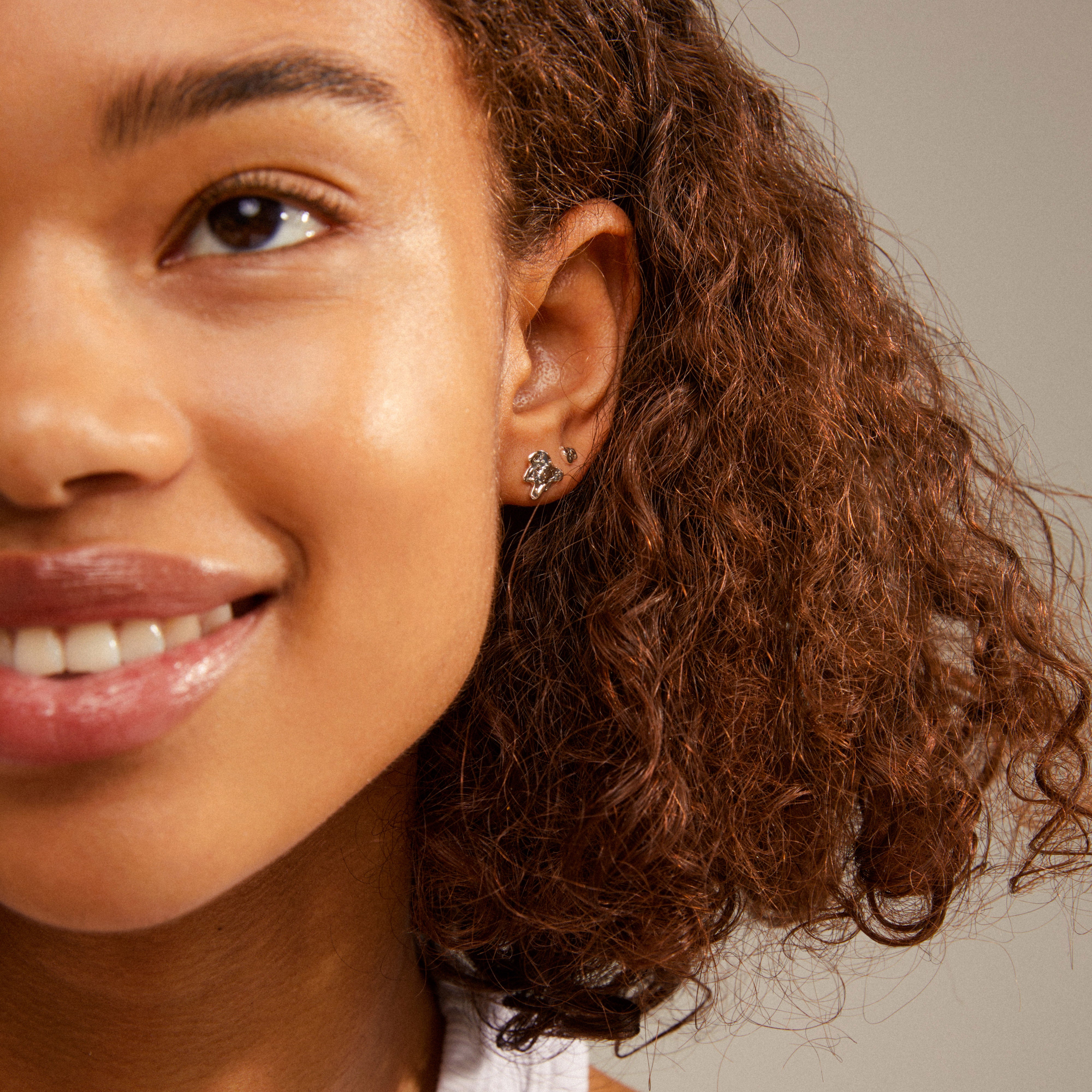 Close-up of a woman's ear adorned with HORIZON silver-plated earrings, showcasing a trendy, mix-and-match ear curation style from Pilgrim.