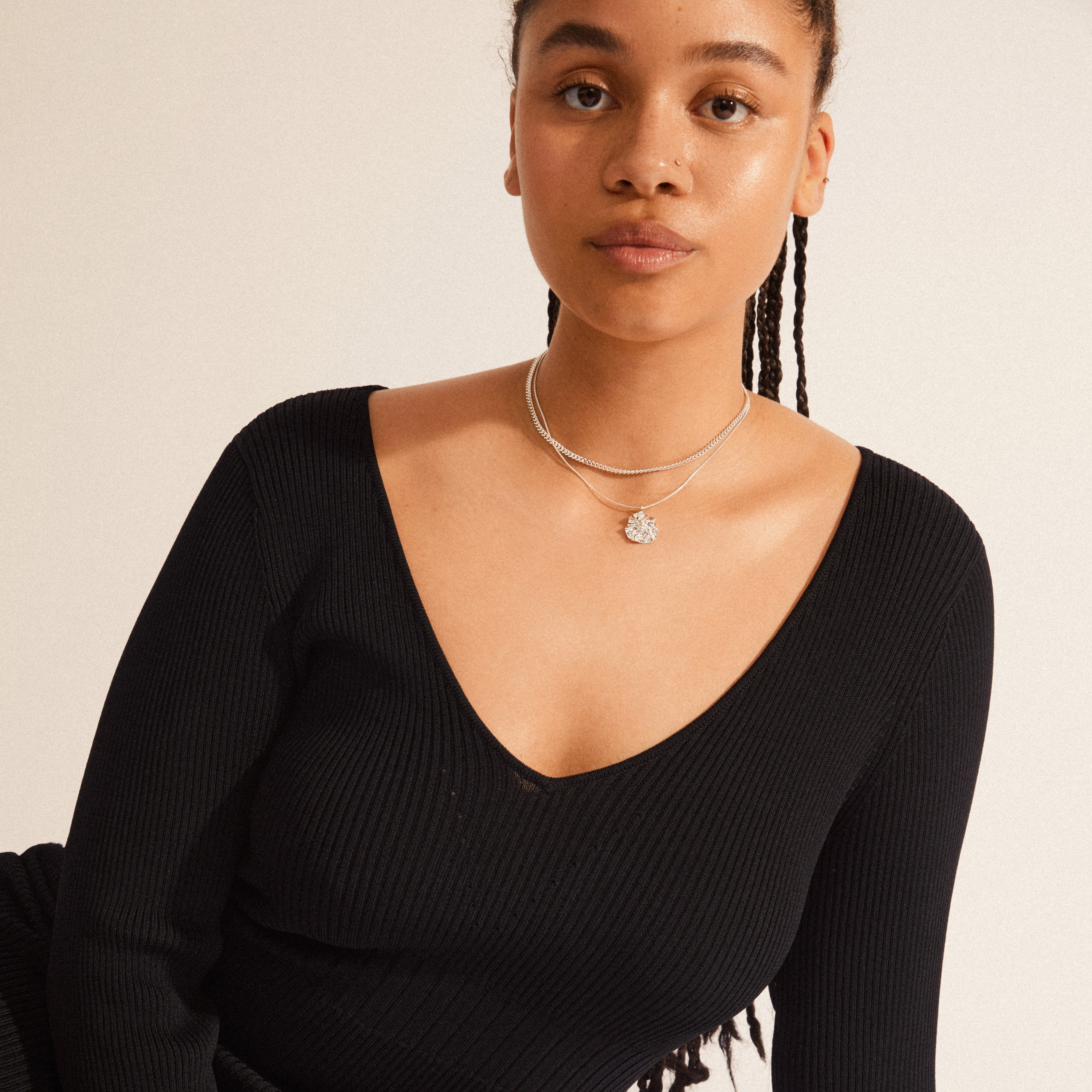 WILLPOWER curb & coin necklace, 2-in-1 set, silver-plated, showcased on a woman wearing a black dress, highlighting the necklace's industrial curb chain and wavy pendant design.