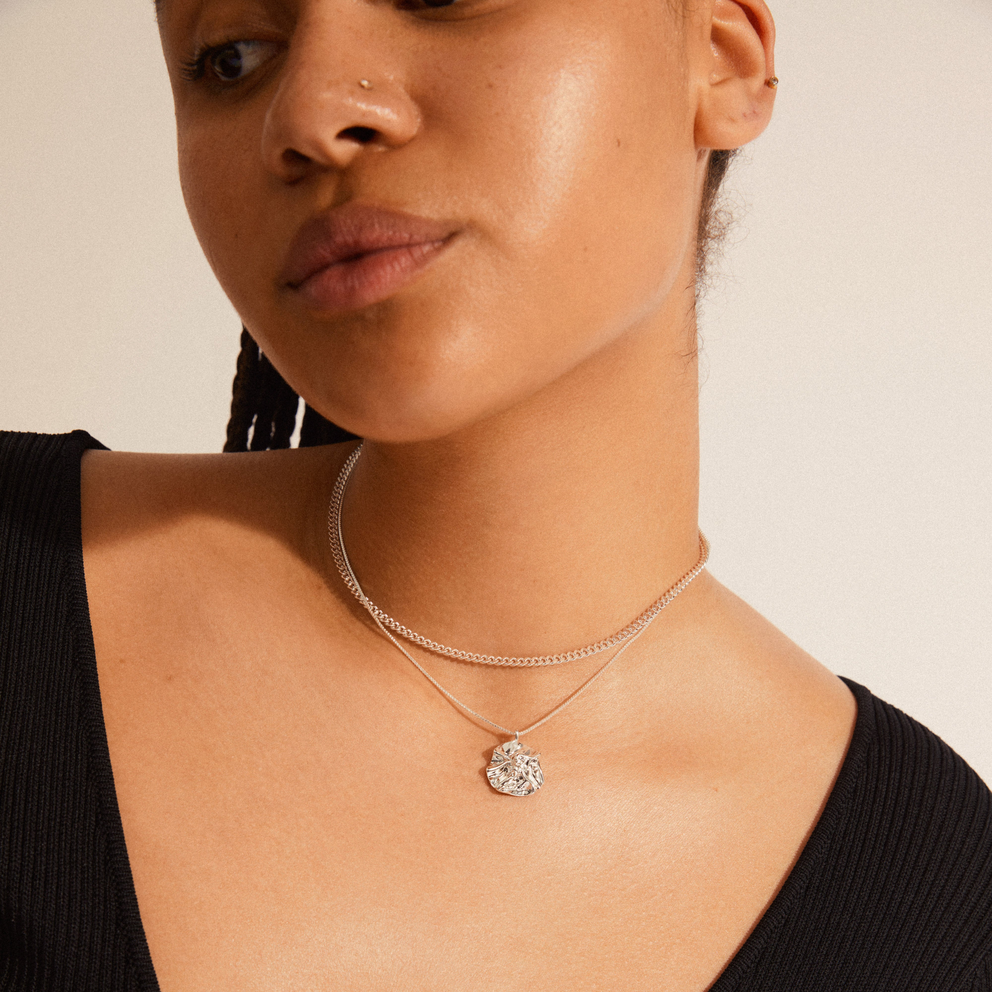 WILLPOWER curb & coin necklace, 2-in-1 set, silver-plated, featuring a raw curb chain and wavy pendant, worn by a woman.