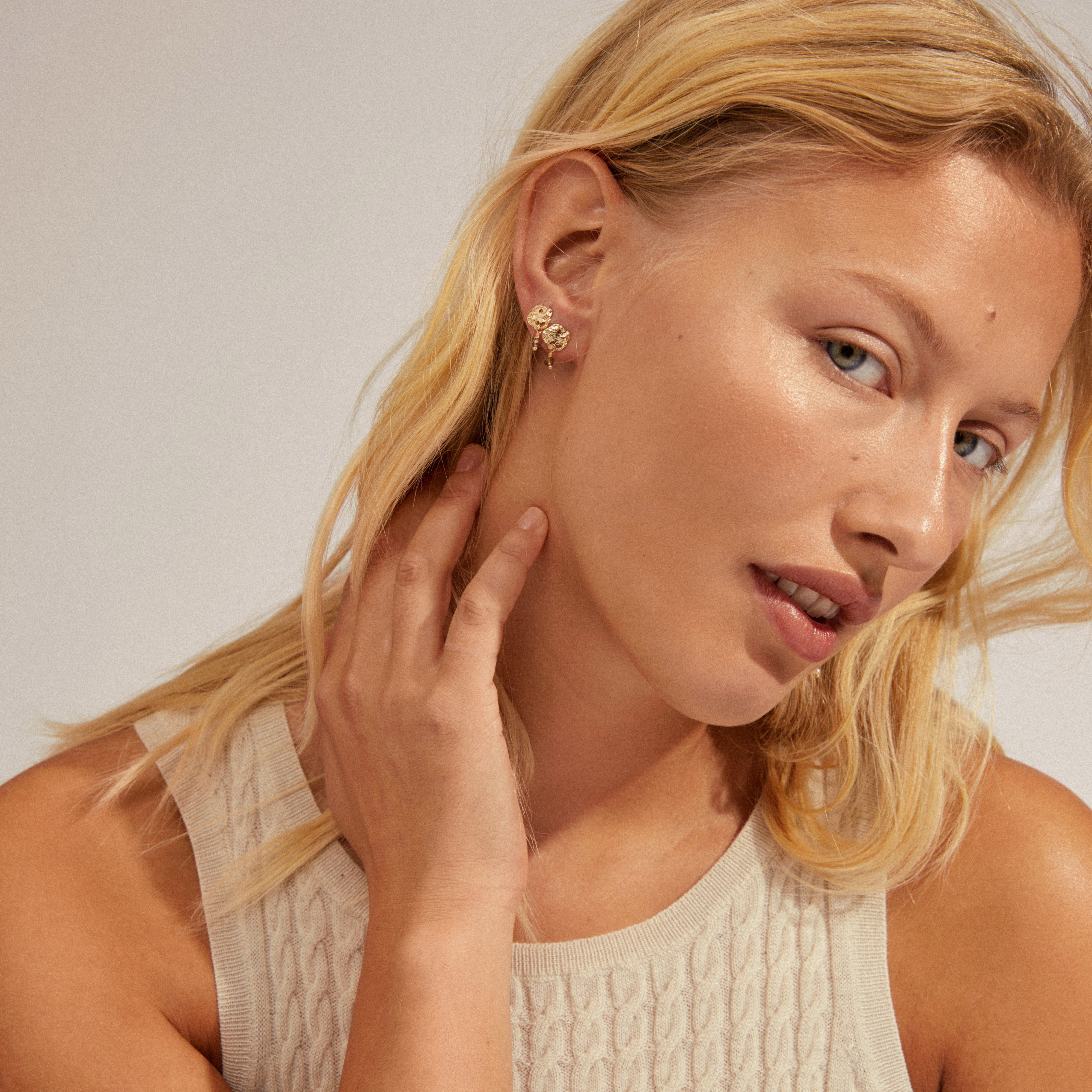 SMILE earrings 2-in-1 set gold-plated, featuring pearl pendants and asymmetrical hooks, showcased by a woman with blonde hair wearing a white shirt.