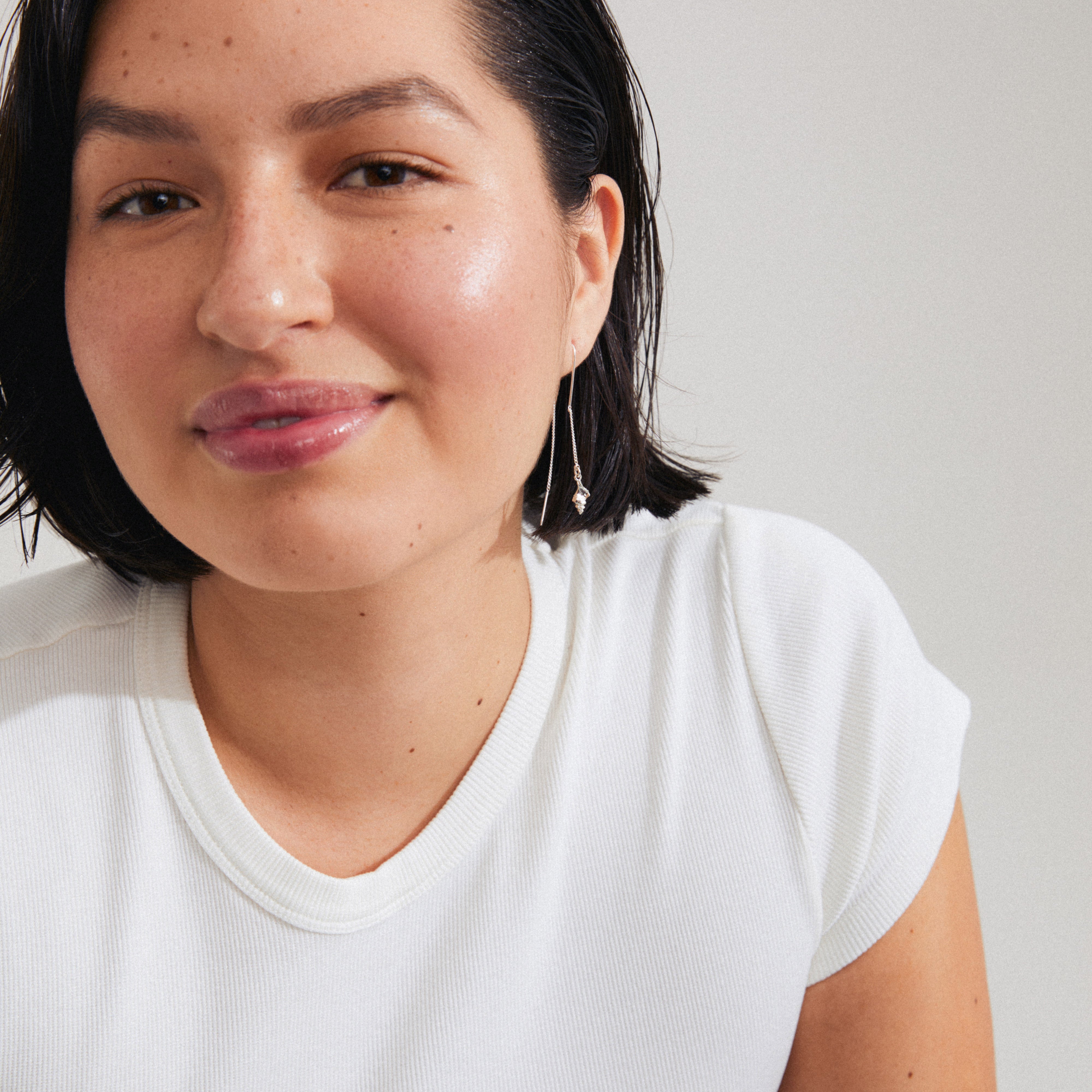 Young woman wearing Pilgrim's SEA chain earrings, silver-plated, showcasing delicate drop design with conch shells, complementing her relaxed, summery look.