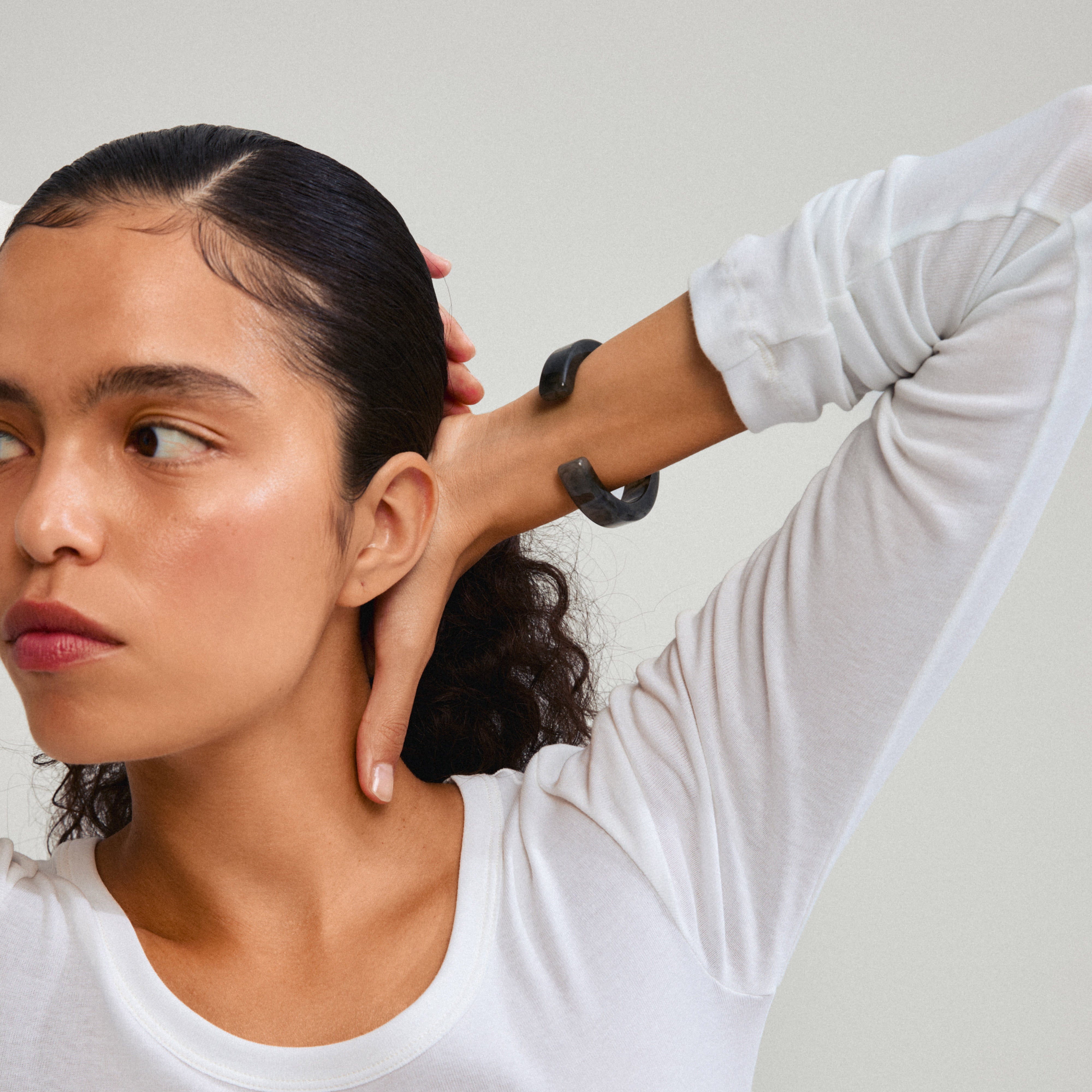 Woman showcasing the ECLIPSE bangle grey by Pilgrim on her wrist, highlighting its trendy marbled grey design and eco-friendly craftsmanship.
