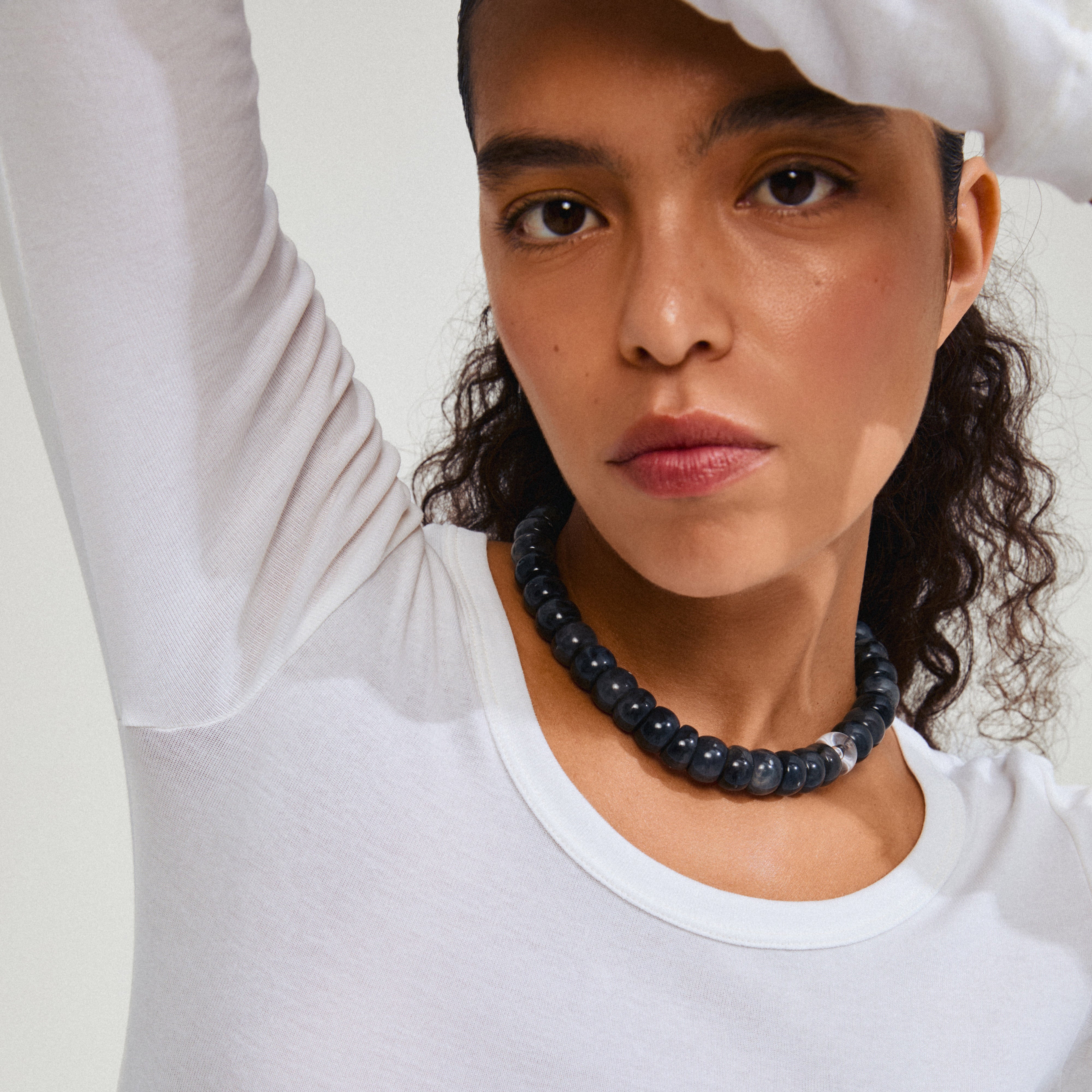 ECLIPSE necklace grey/gold-plated: Woman wearing a white shirt and black beaded necklace, showcasing the necklace's chunky, recycled acrylic beads and gold-plated extension chain.