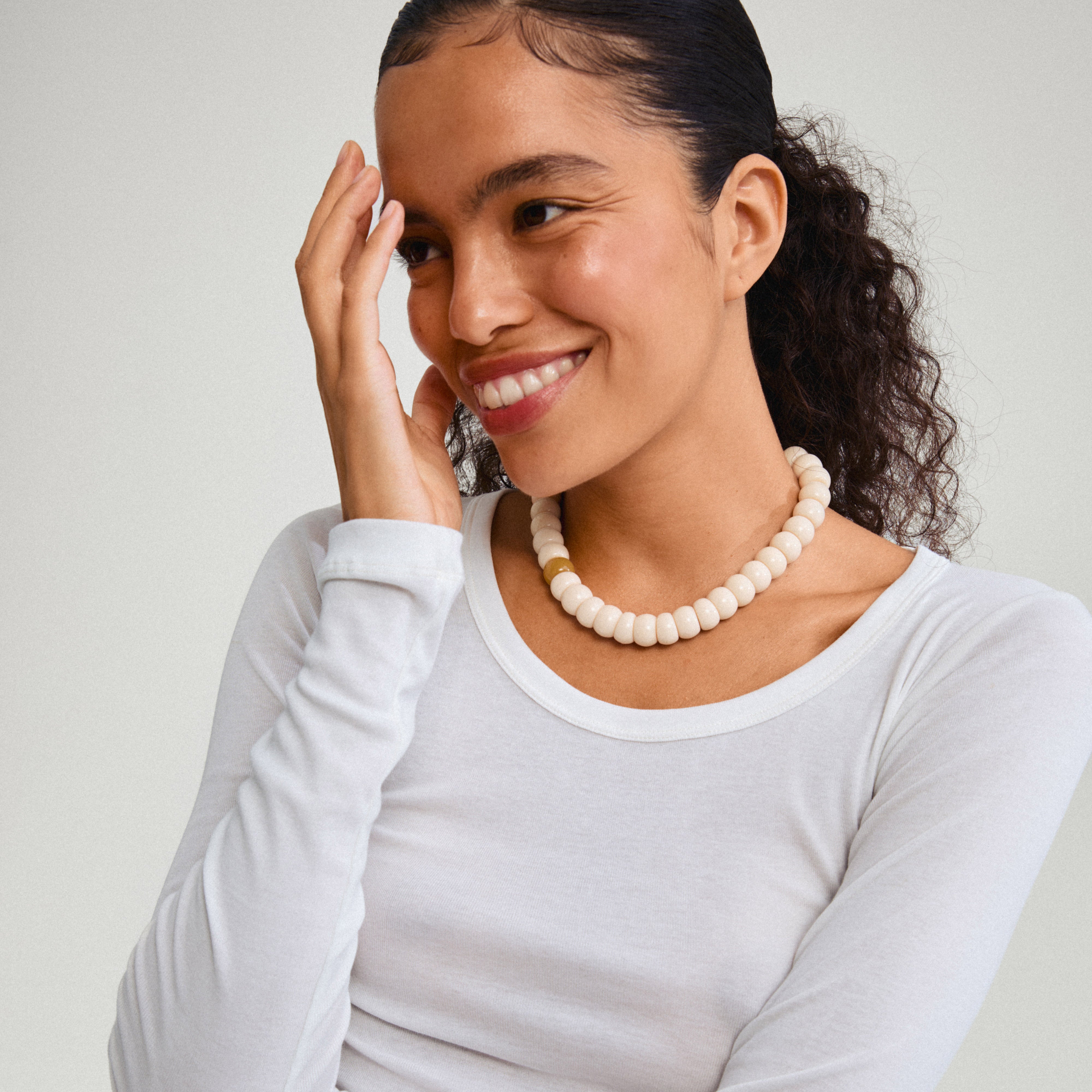 ECLIPSE necklace white/silver-plated showcased on a smiling woman, featuring chunky ivory beads, reflecting Pilgrim's blend of timeless and trendy Scandinavian style.