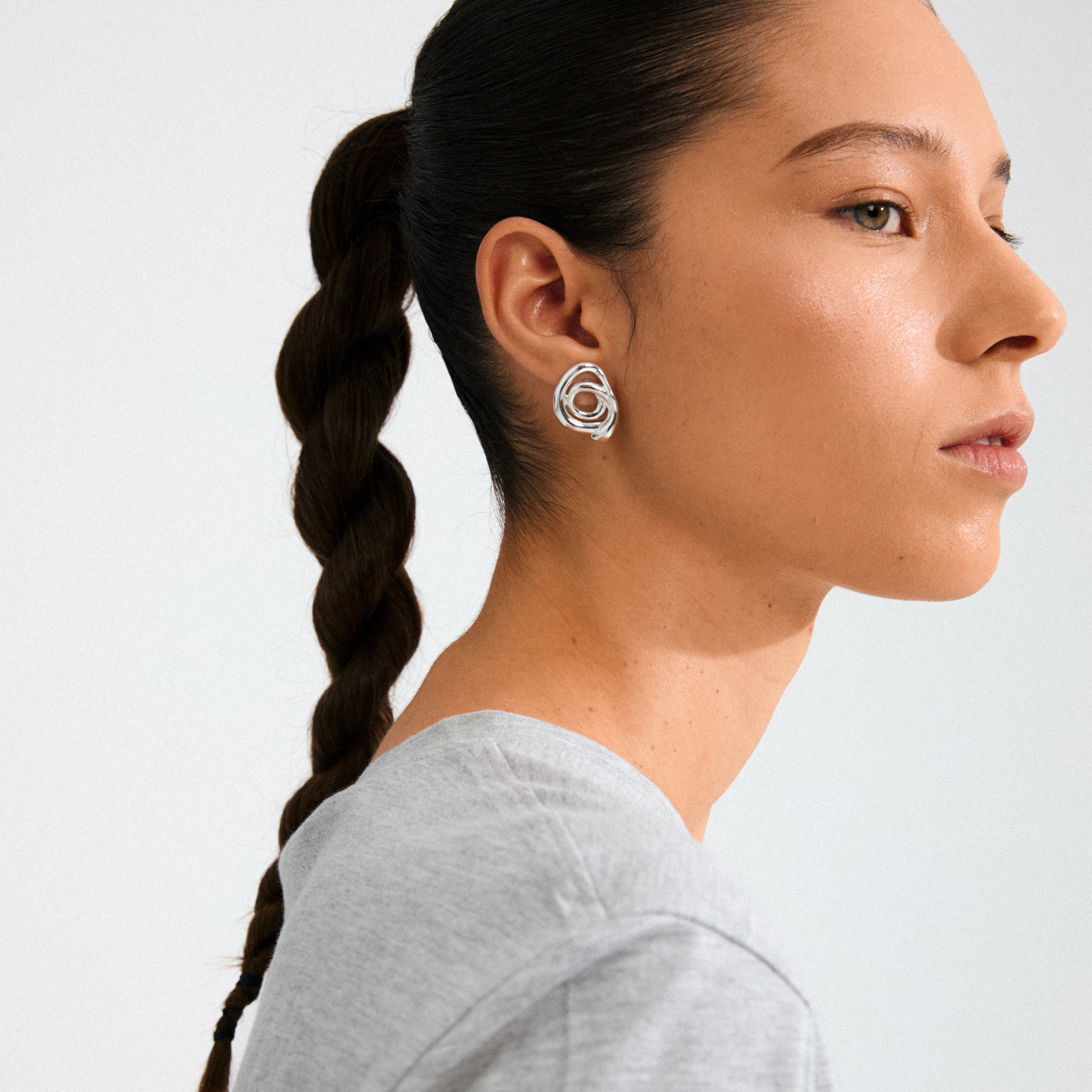 Side profile of a young woman wearing Pilgrim's UNFOLD silver-plated earrings, showcasing their intricate, artistic design and playful, indie-inspired style.