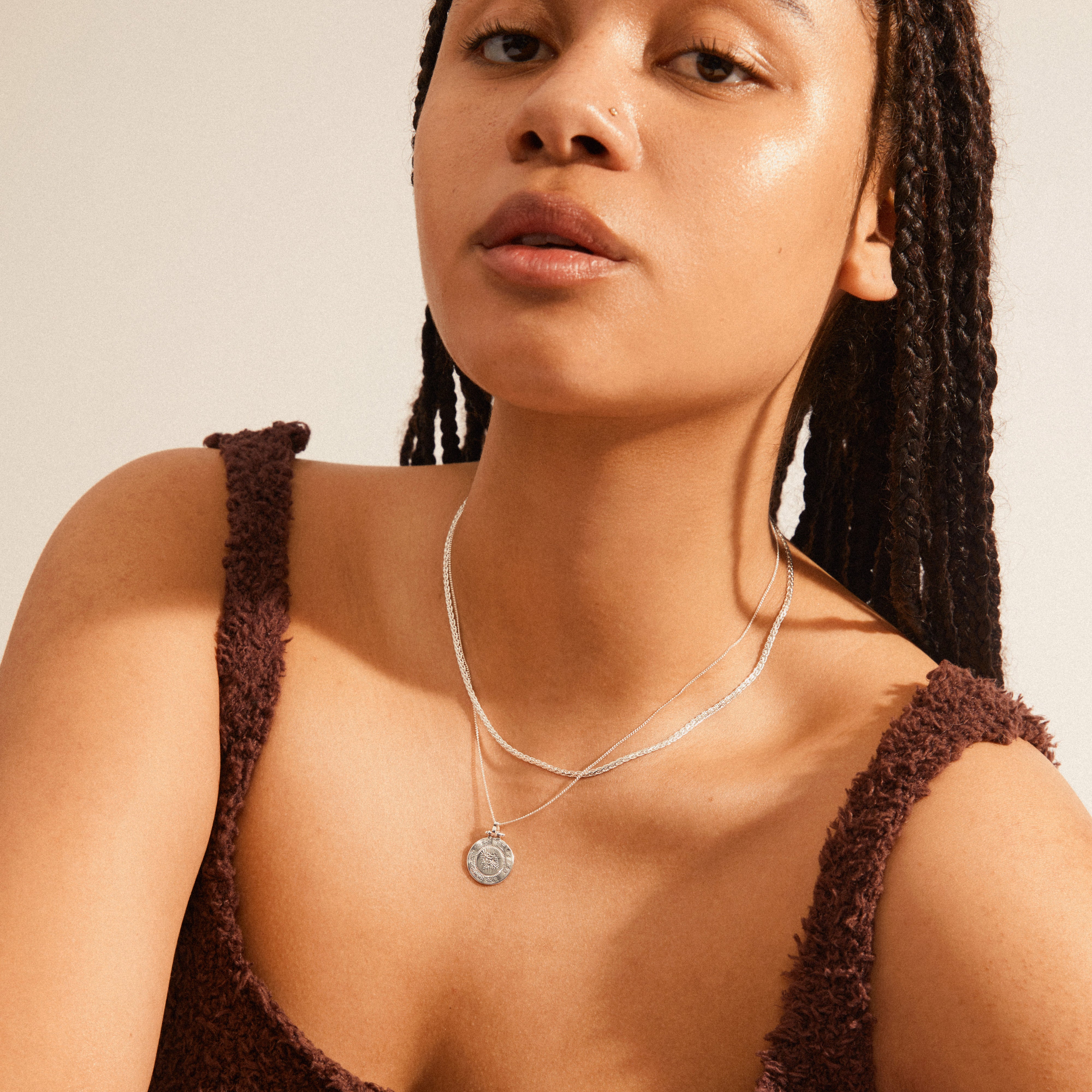 NOMAD 2-in-1 coin necklace silver-plated worn by a woman with braids, showcasing layered coin chains for a trendy, everyday look.