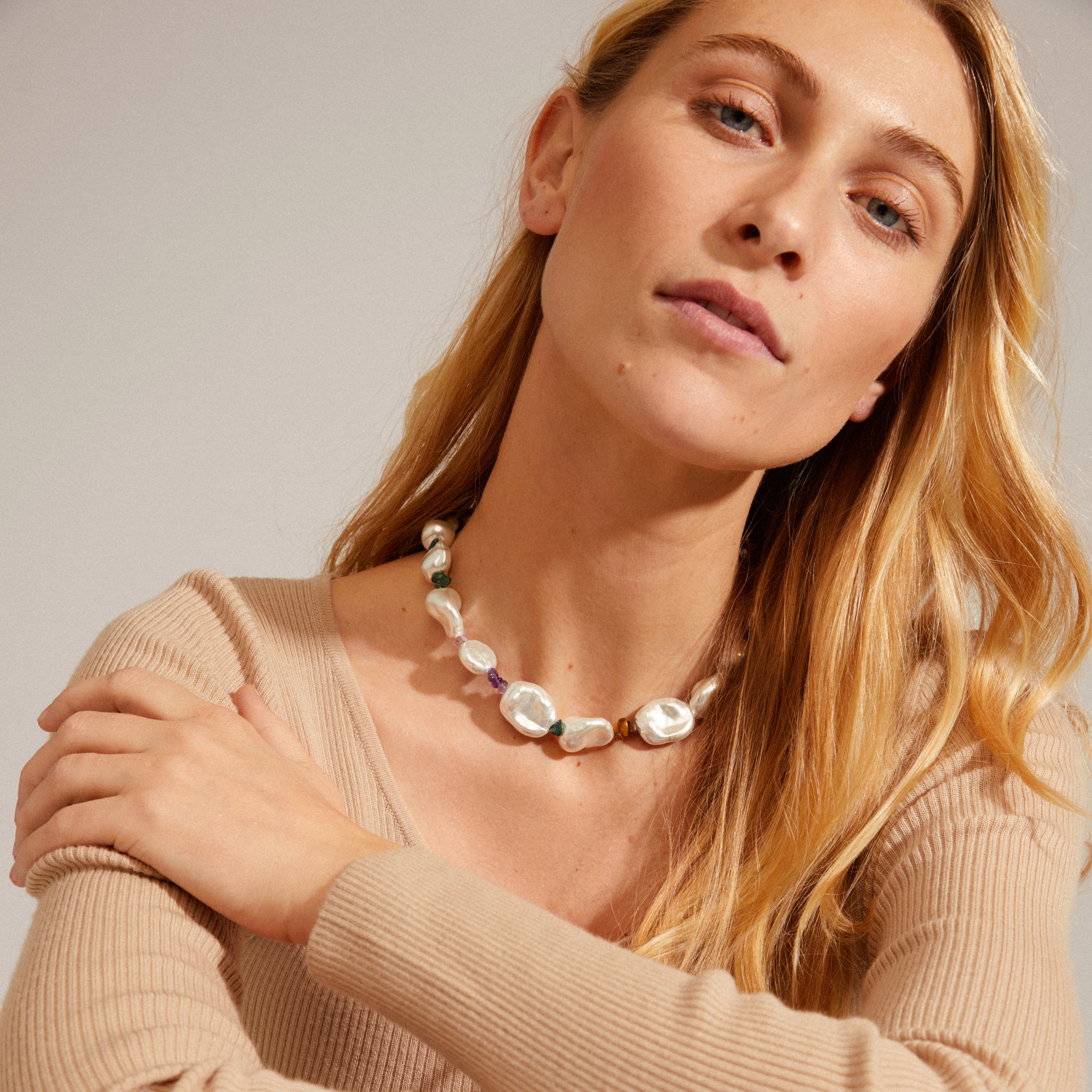 Silver-plated RHYTHM pearl necklace featuring asymmetrical shapes and semi-precious stones, worn by a woman, showcasing its luxurious boho style and eye-catching volume.