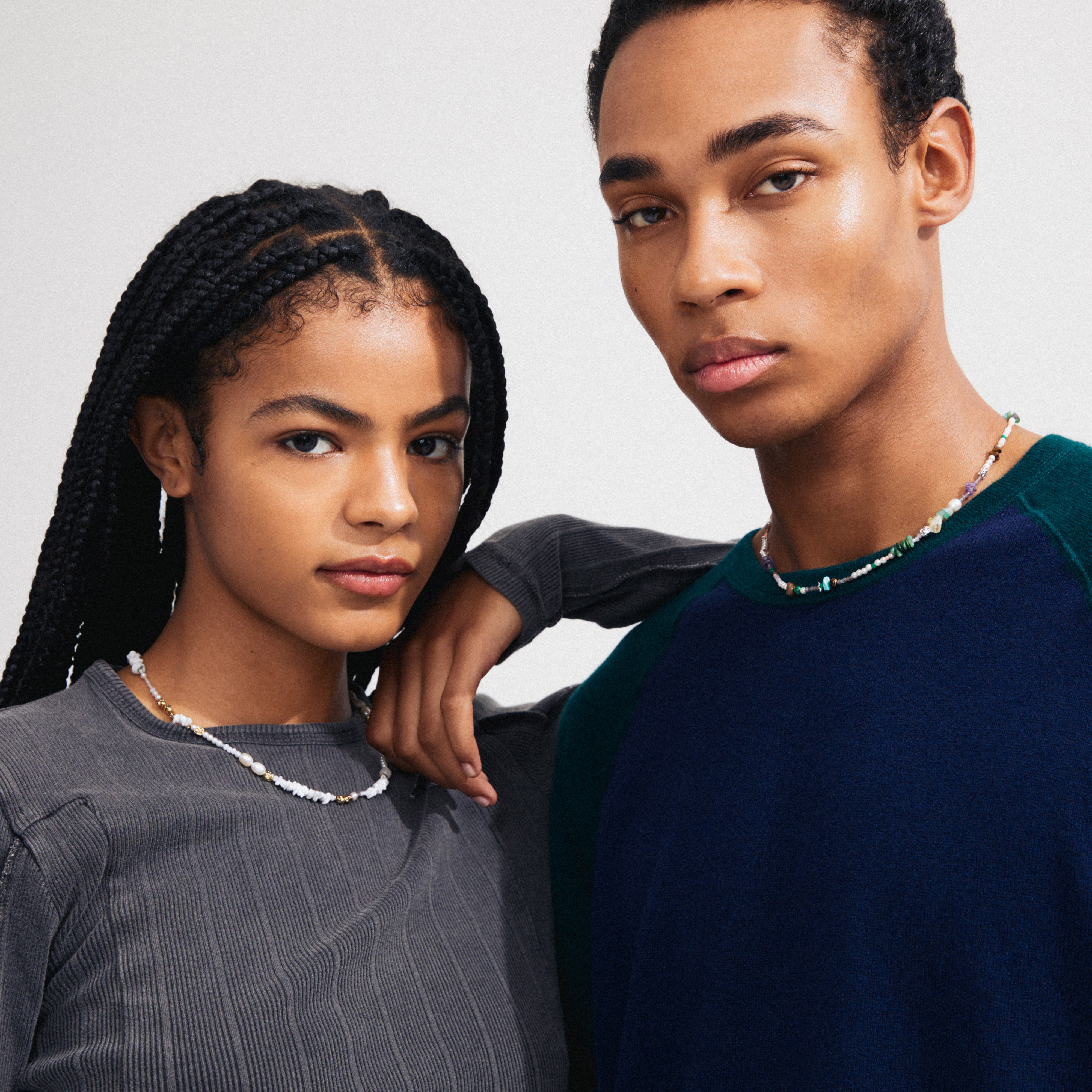 Two young adults showcase Pilgrim's FORCE necklace, featuring genuine freshwater pearls and semi-precious stones, reflecting a blend of timeless and trendy Scandinavian jewellery.