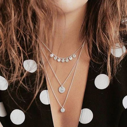 A woman wearing the ARDEN 3-in-1 crystal necklace, silver-plated, showcasing its intricate ethnic-inspired design with amulets and crystals, nestling elegantly at the décolletage.