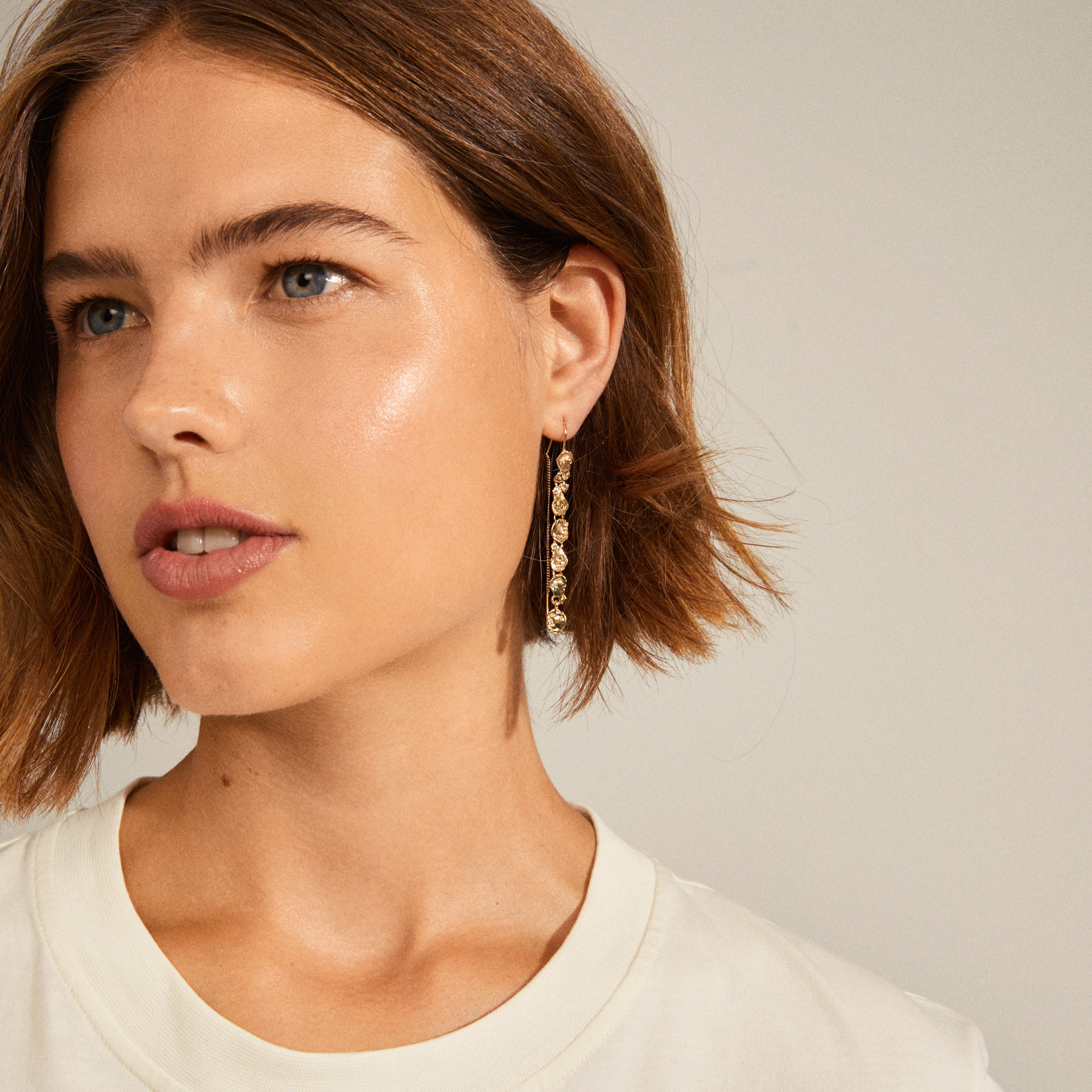 Close-up of THANKFUL long chain earrings gold-plated from Pilgrim, showcasing natural raw shapes and organic design for a classy, down-to-earth vibe.