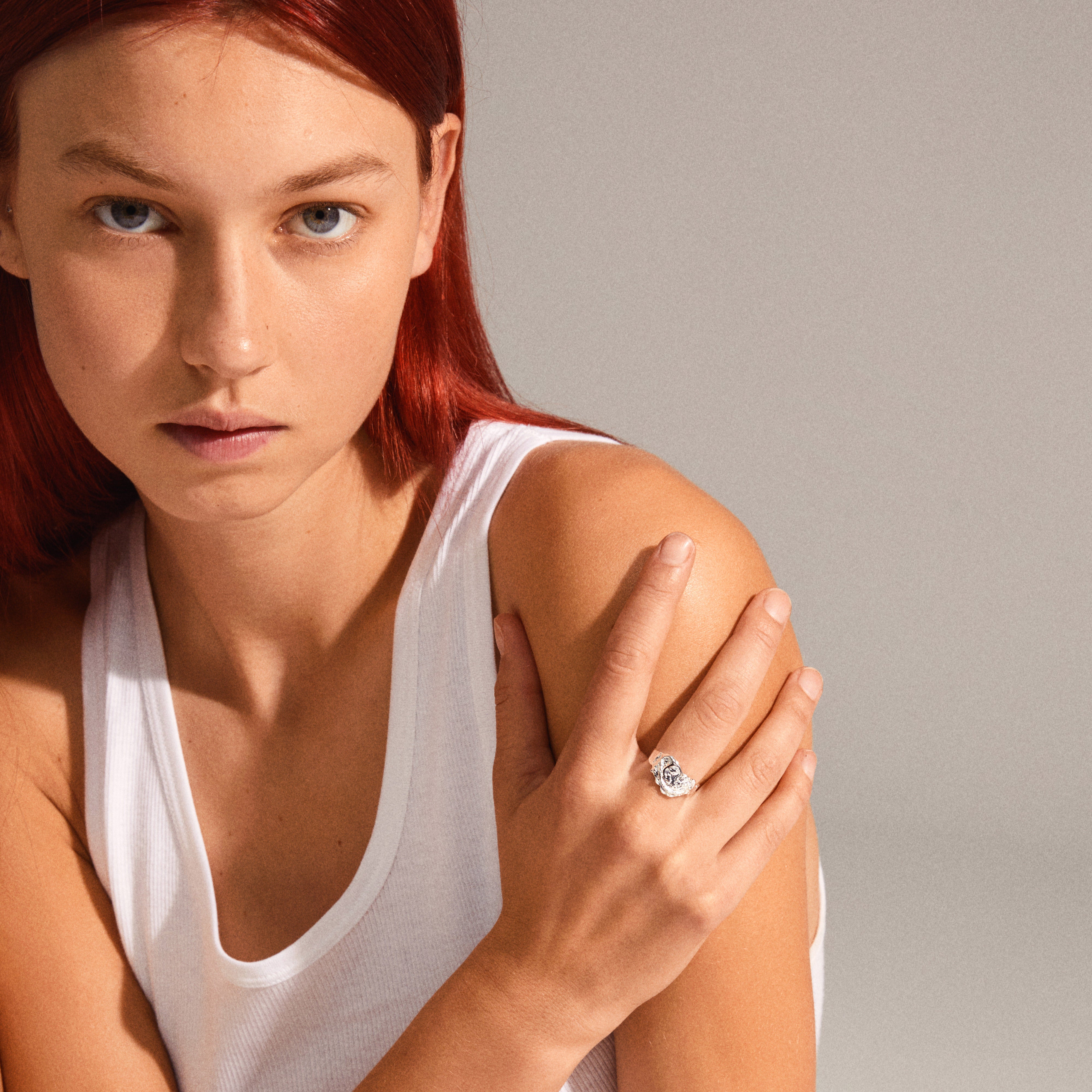 Woman wearing a white tank top showcases Pilgrim's BLOSSOM organic-shaped silver-plated ring, featuring handcrafted, irregular design, emphasizing eco-friendly, recycled materials.