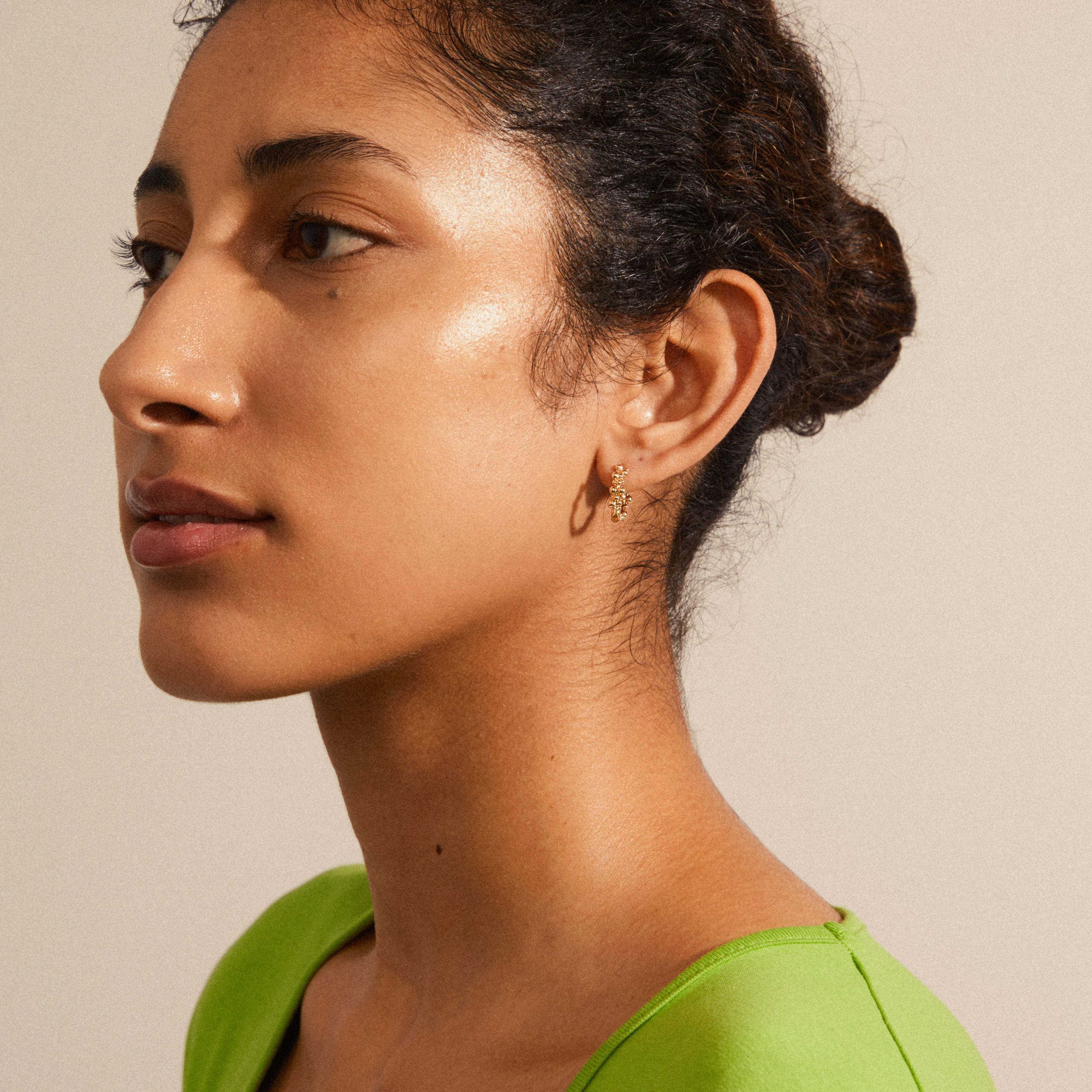 Woman wearing Pilgrim's SOLIDARITY small bubbles hoop earrings, gold-plated, showcasing a playful and energetic spherical design.
