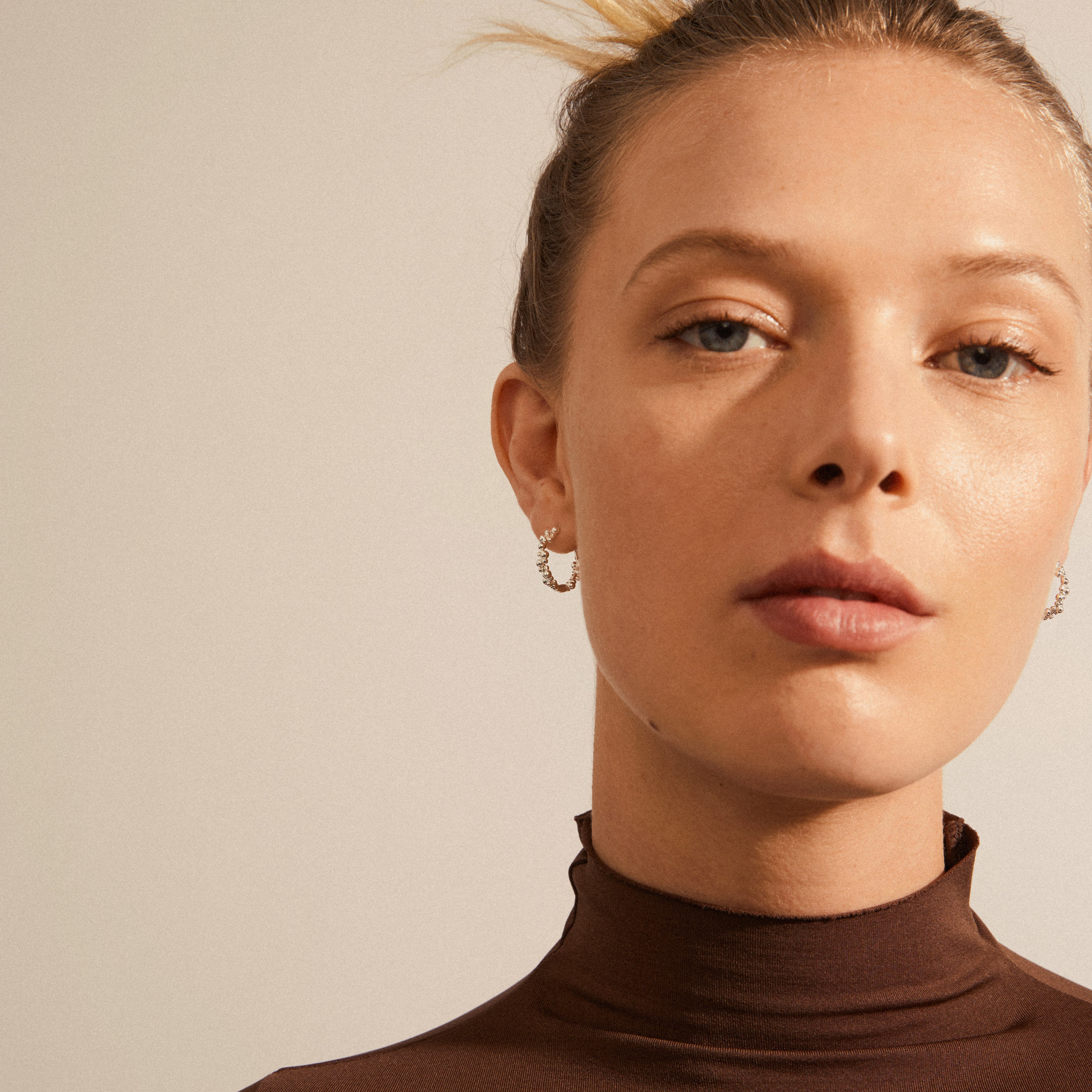 Woman wearing Pilgrim's SOLIDARITY small bubbles hoops, silver-plated, showcasing spherical design that adds a playful, energetic touch to her look.