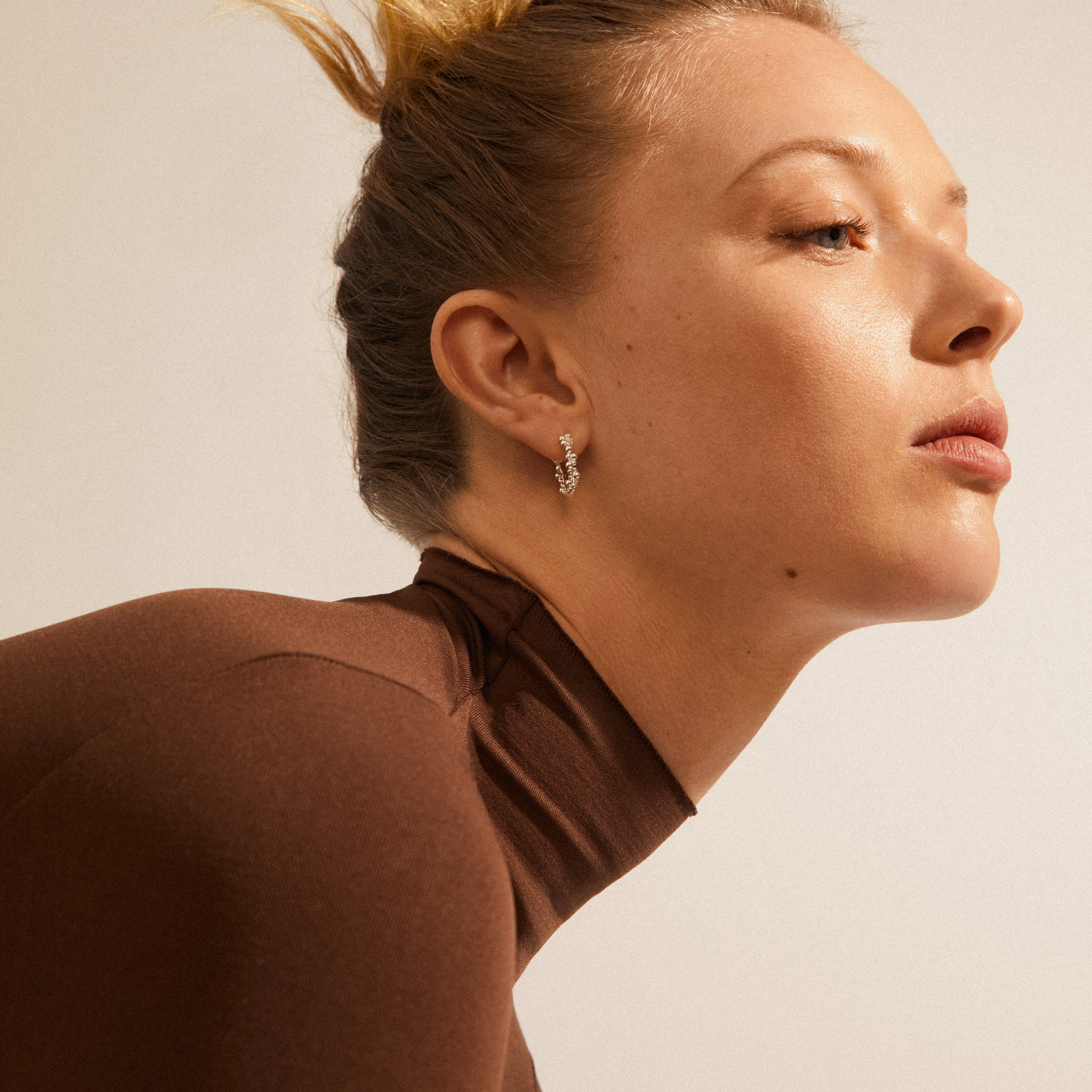 SOLIDARITY small bubbles hoops, silver-plated, worn by a woman with pulled-back hair, showcasing playful spherical design and shine, embodying style and sustainability.