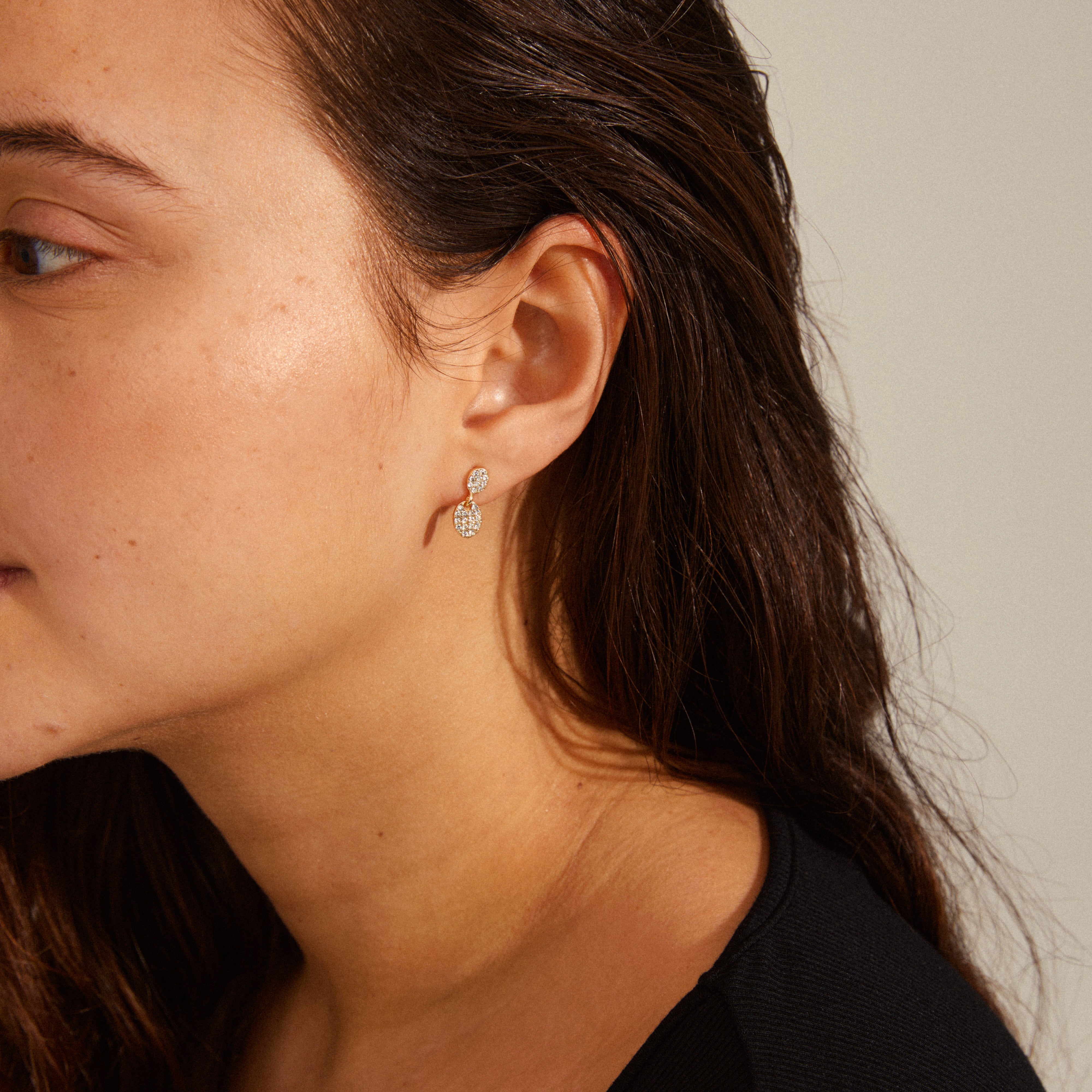 BEAT crystal earrings gold-plated, featuring oval pendants with Preciosa crystals, elegantly styled on a woman's ear. Perfect blend of simplicity and sophistication.