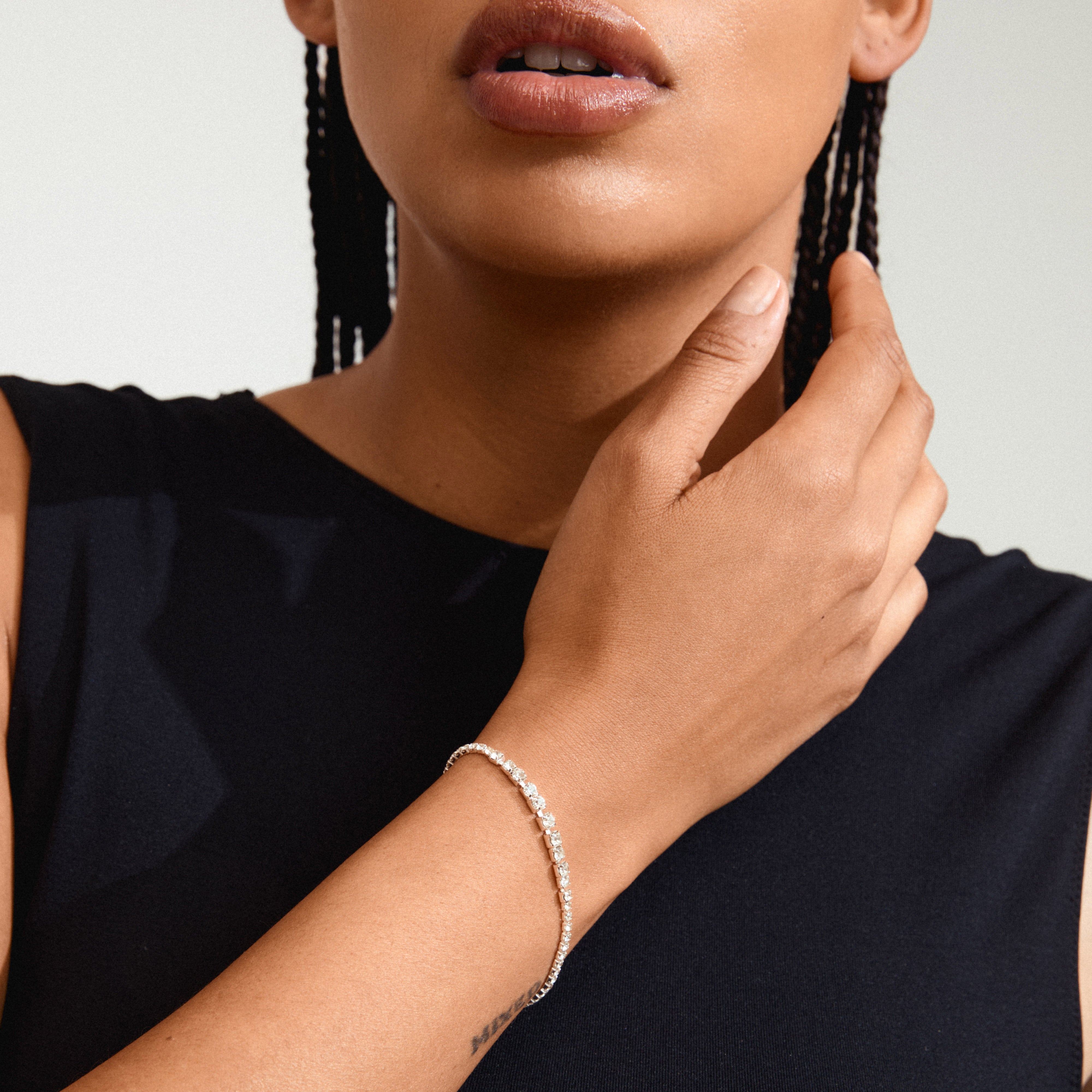 Woman wearing a black dress, showcasing the SKY bracelet silver-plated by Pilgrim, adorned with shiny Preciosa crystals and an adjustable slide lock for perfect fit.