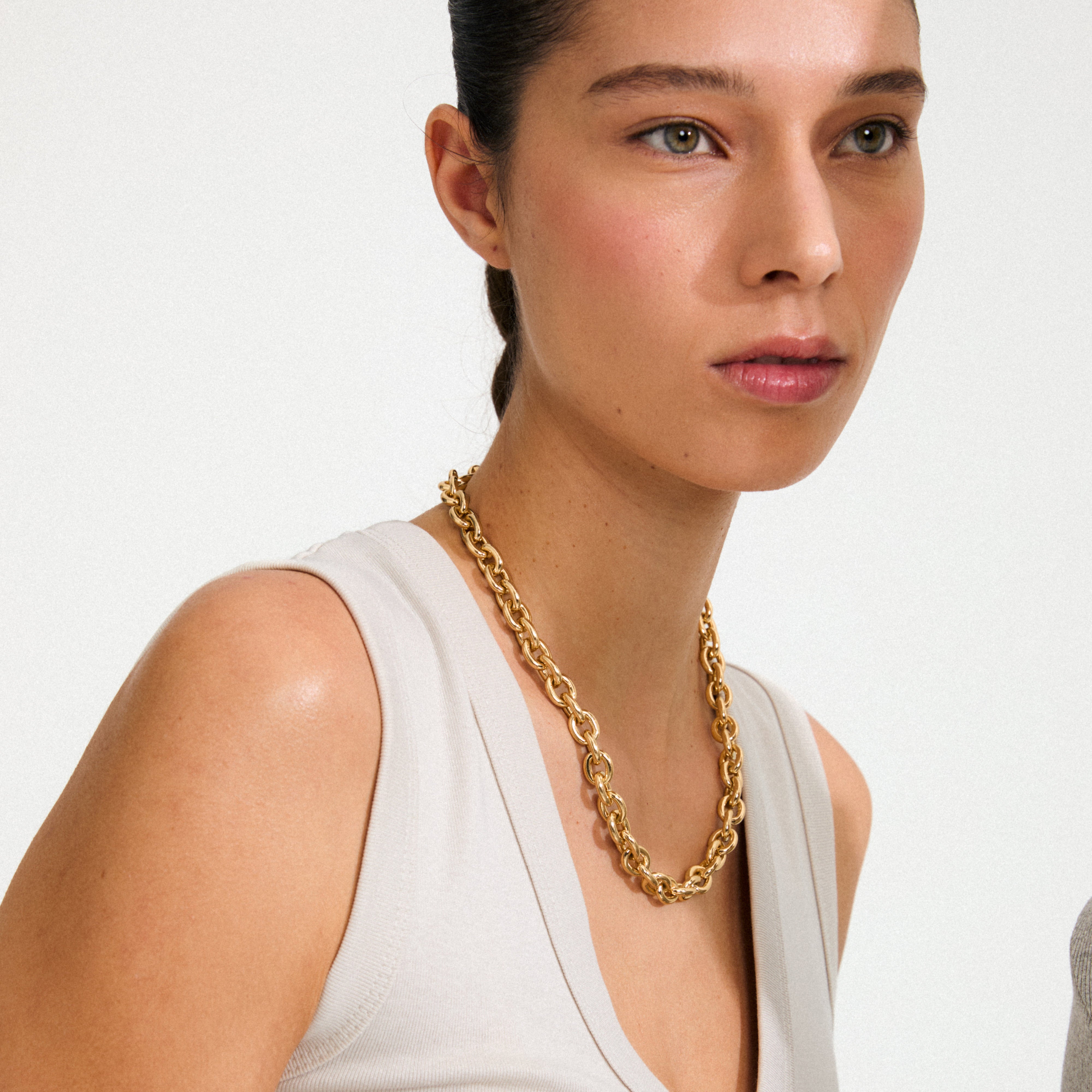 Close-up of a woman wearing Pilgrim's PHASE necklace, a gold-plated, chunky chain with a decorative lobster clasp, embodying urban chic and timeless style.