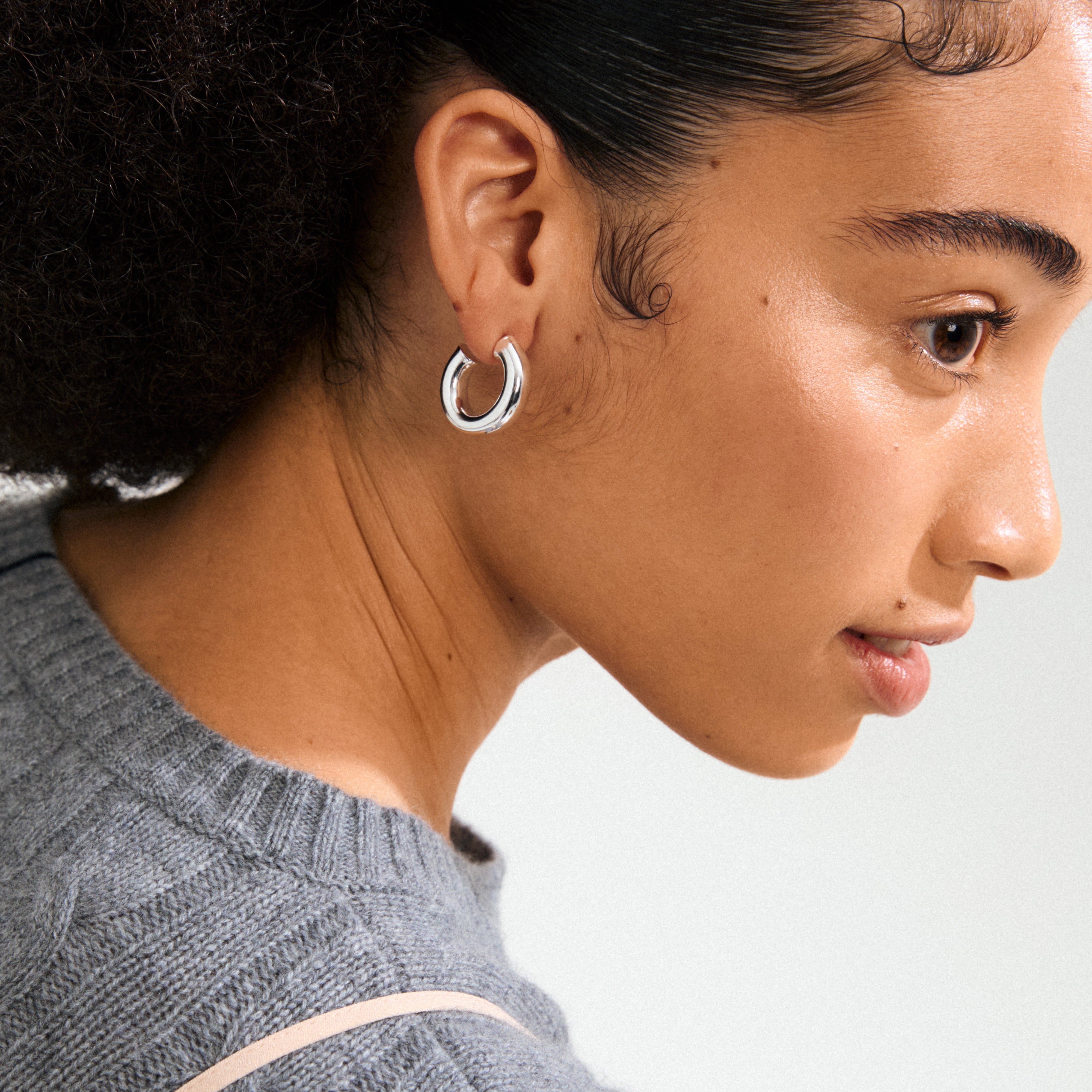 Profile of a young person wearing Pilgrim's PHASE large silver-plated hoops, showcasing chunky design and refined style with a recycled material focus.