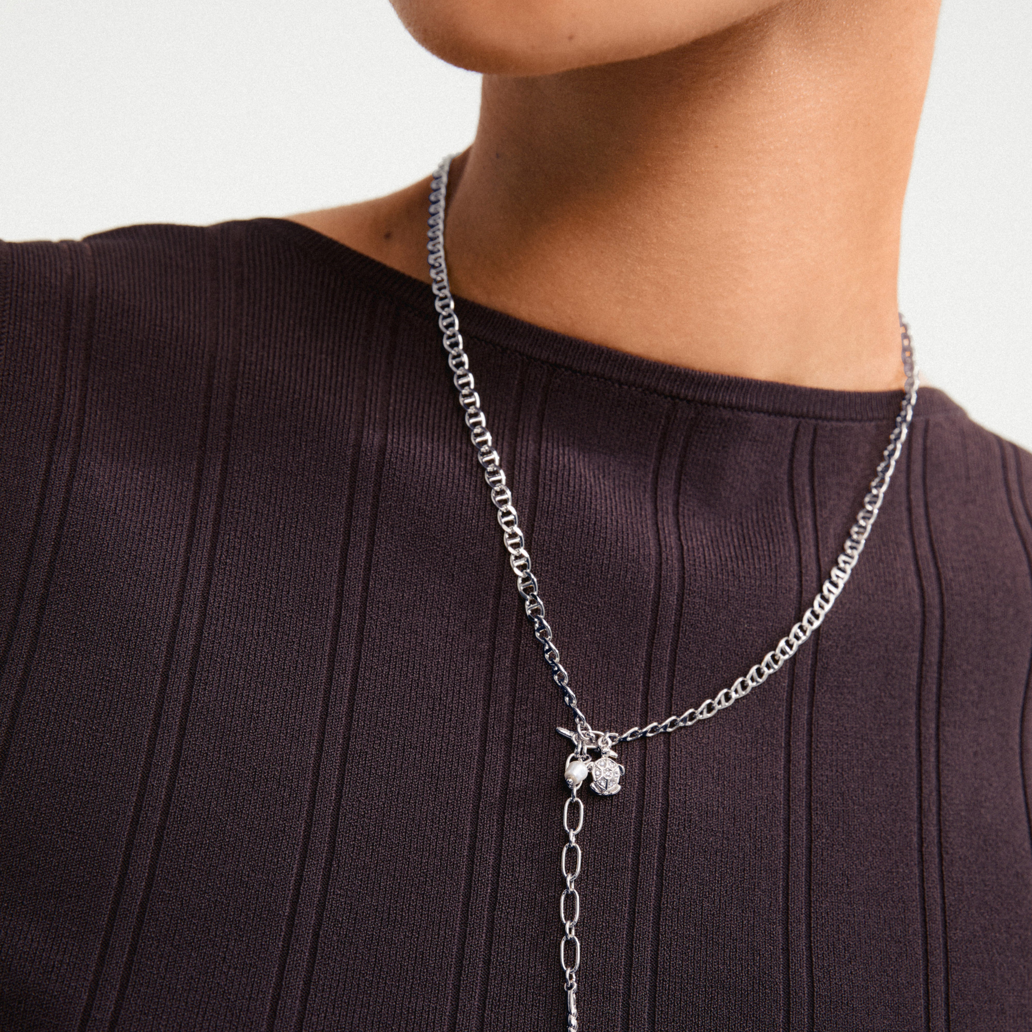 Woman wearing Pilgrim's BREEZE necklace 2-in-1 set, featuring a silver-plated anchor chain with turtle pendant and pearl bead chain, layered for a boho luxe style.