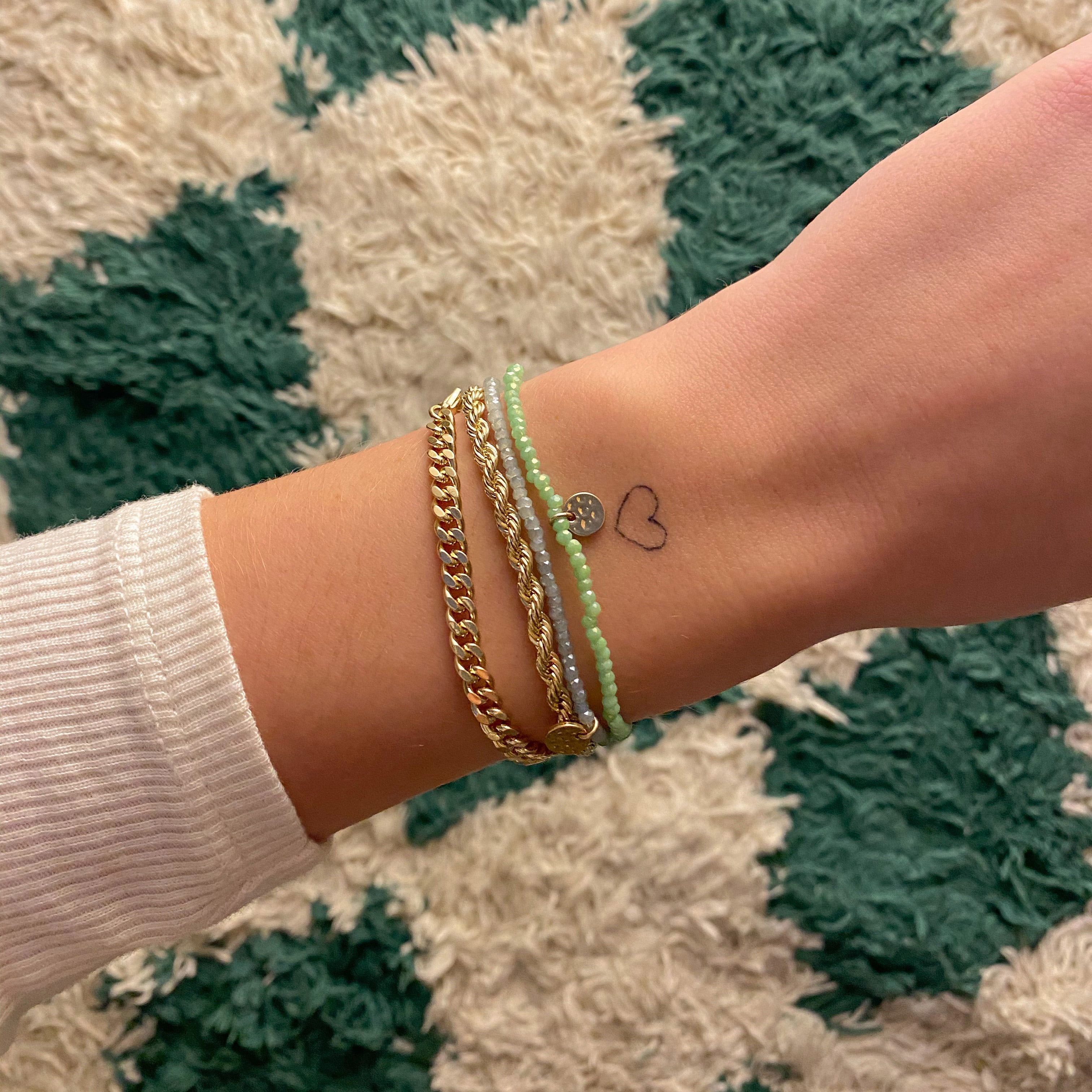 INDIE bracelet green, gold-plated, on wrist with other bracelets; features faceted glass beads and Pilgrim logo, perfect for stacking.