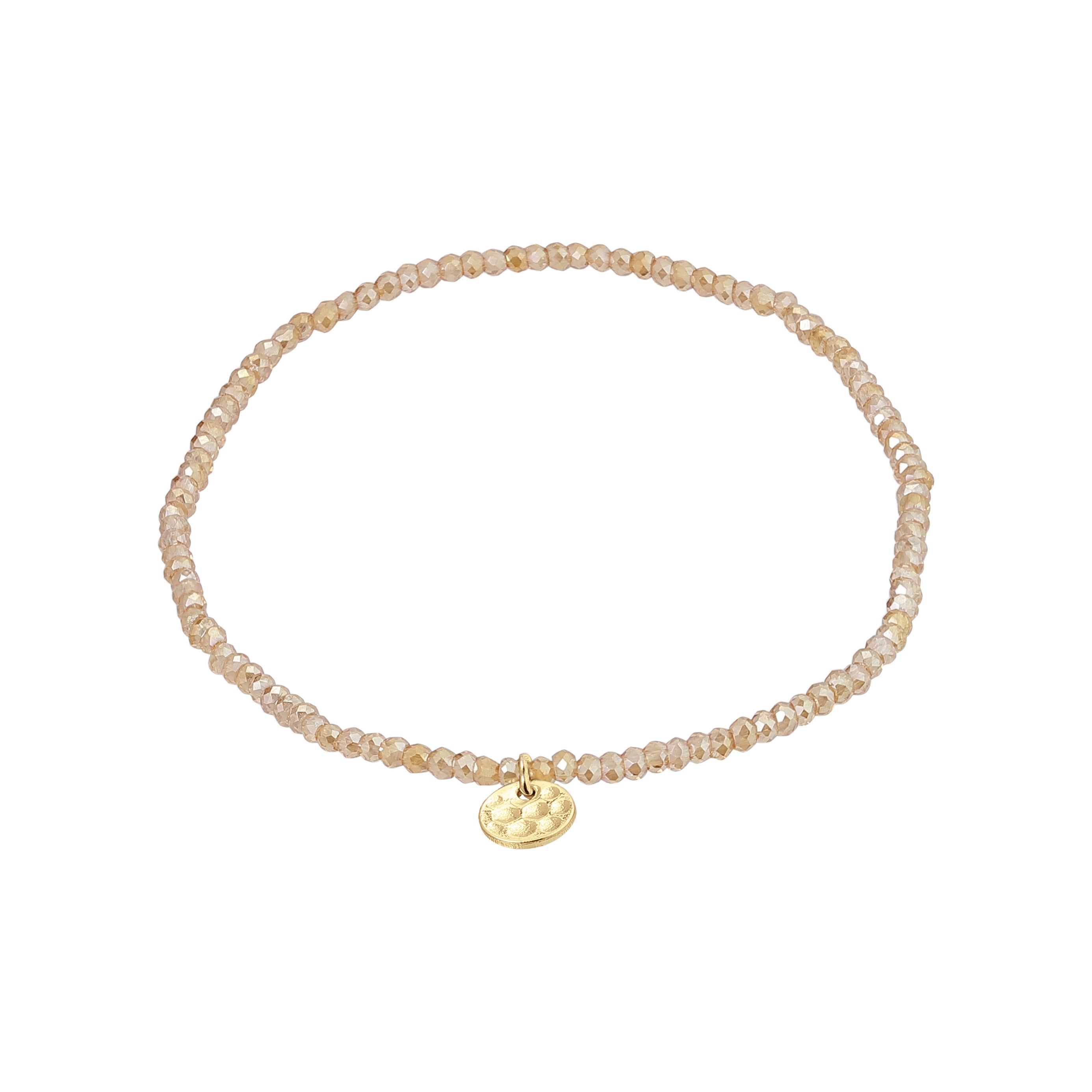 INDIE bracelet in peach with gold-plated charm, featuring faceted glass beads and elastic fit, embodies Pilgrim's blend of timeless style and modern trend.