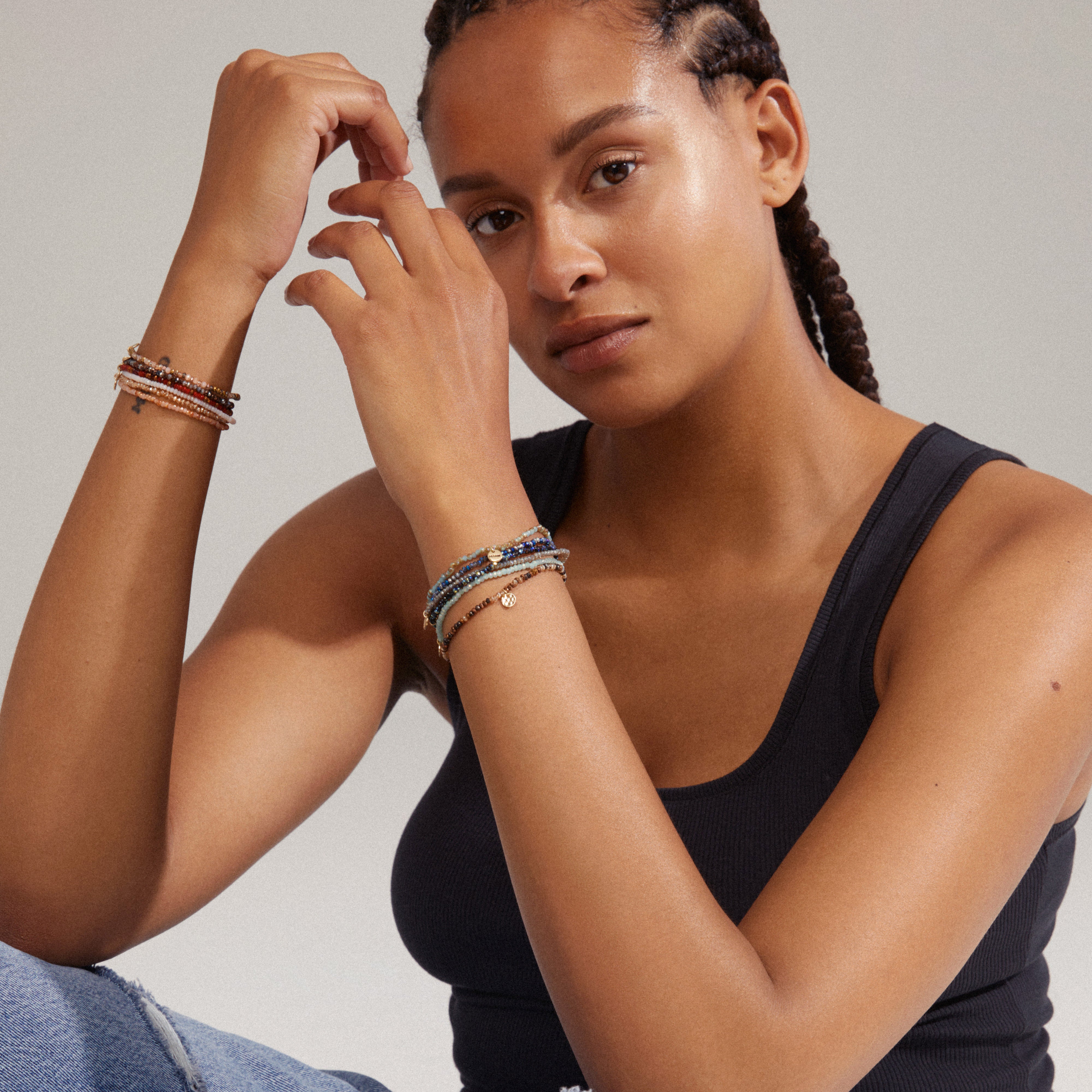 INDIE bracelet featuring dark grey faceted glass beads and a discreet gold-plated Pilgrim logo, worn by a woman with braided hair, showcasing its elegant design.