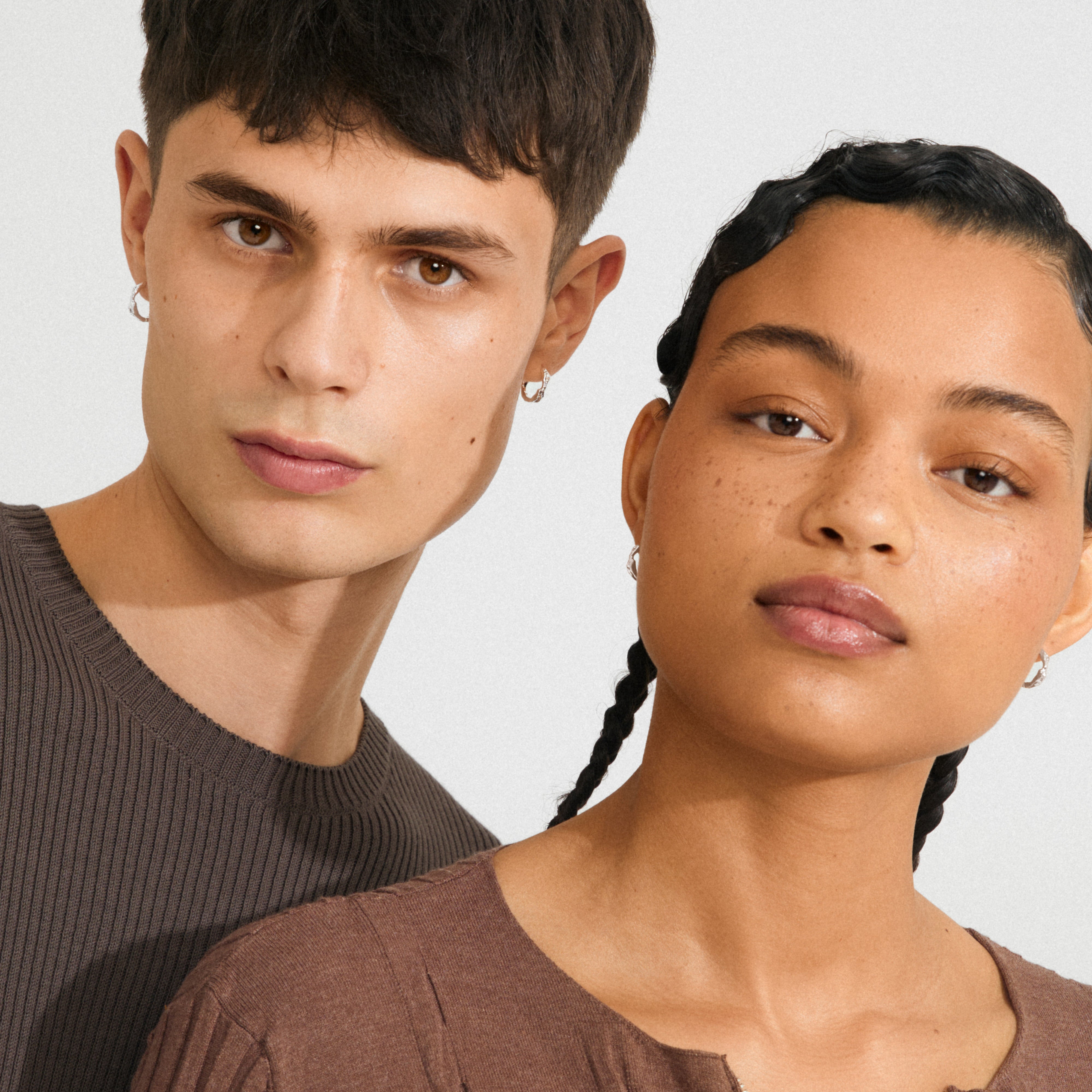 Two people wearing ZION small huggie hoop earrings silver-plated, showcasing the earrings' playful, classy design, perfect for a chic, effortless style.