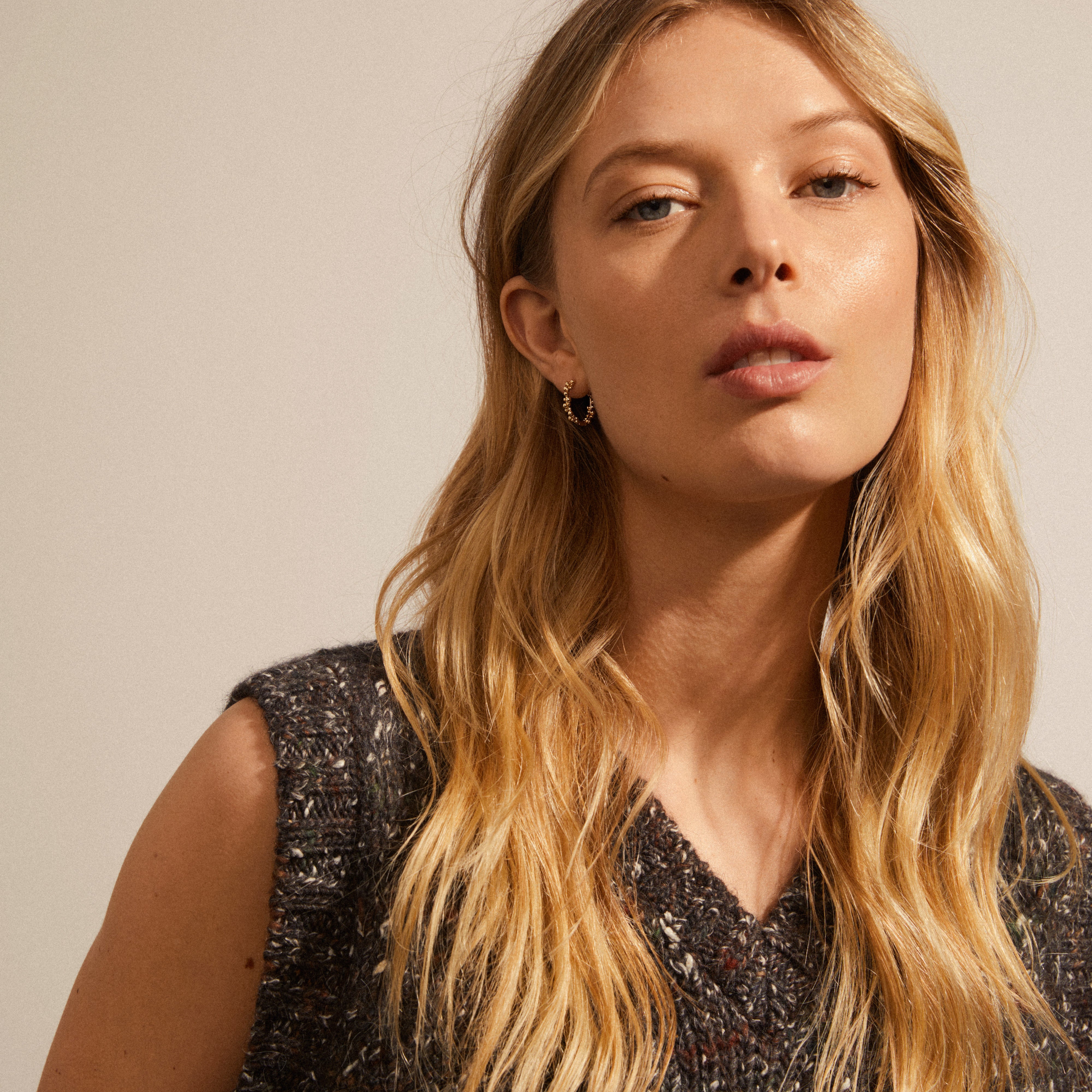 Close-up of a woman wearing SOLIDARITY medium bubbles hoop earrings, gold-plated with asymmetric bubble shapes, showcasing playful structure and dynamic silhouette.
