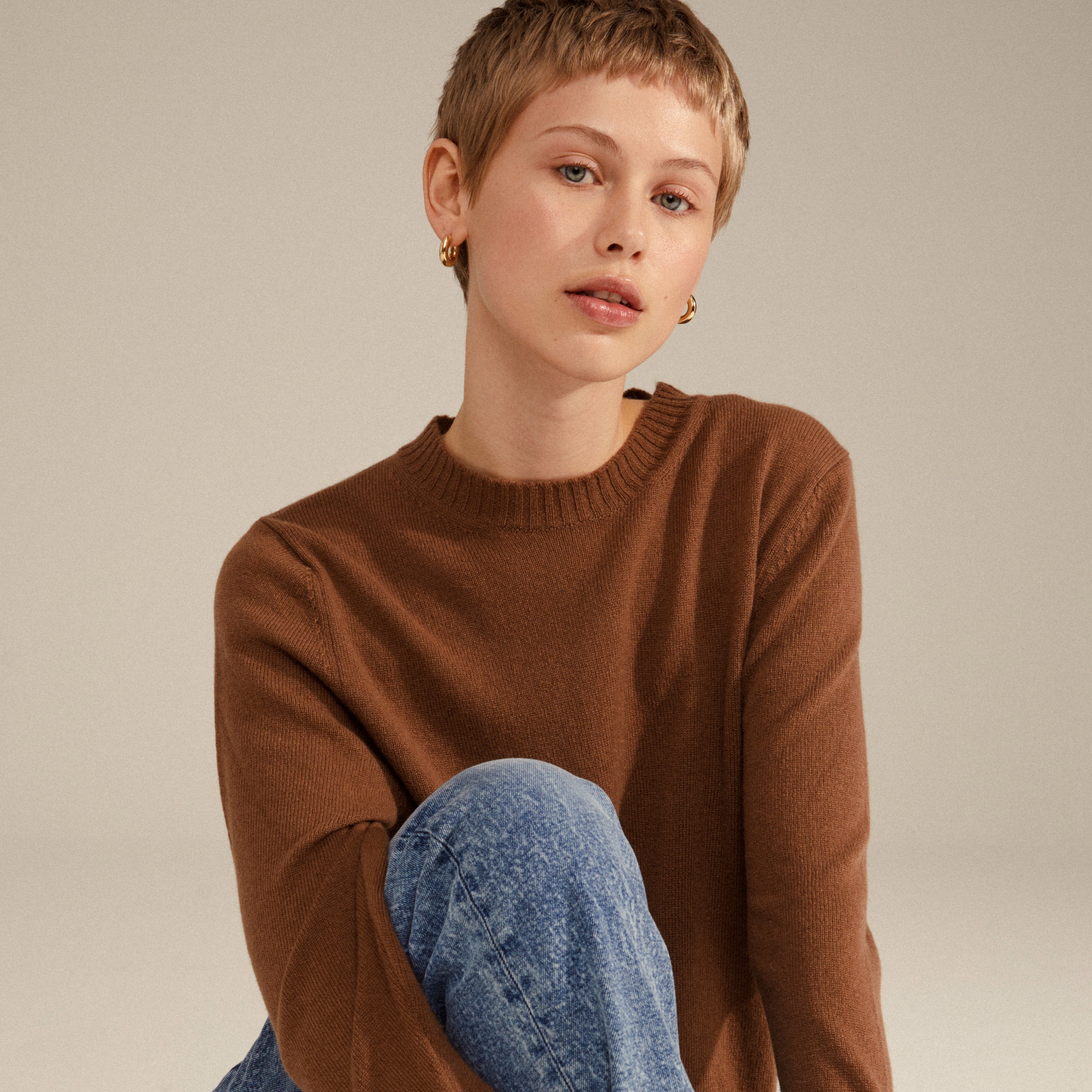 A woman showcases AICA chunky gold-plated hoop earrings, highlighting their timeless, chunky design, perfect for everyday wear and trendy ear curation.