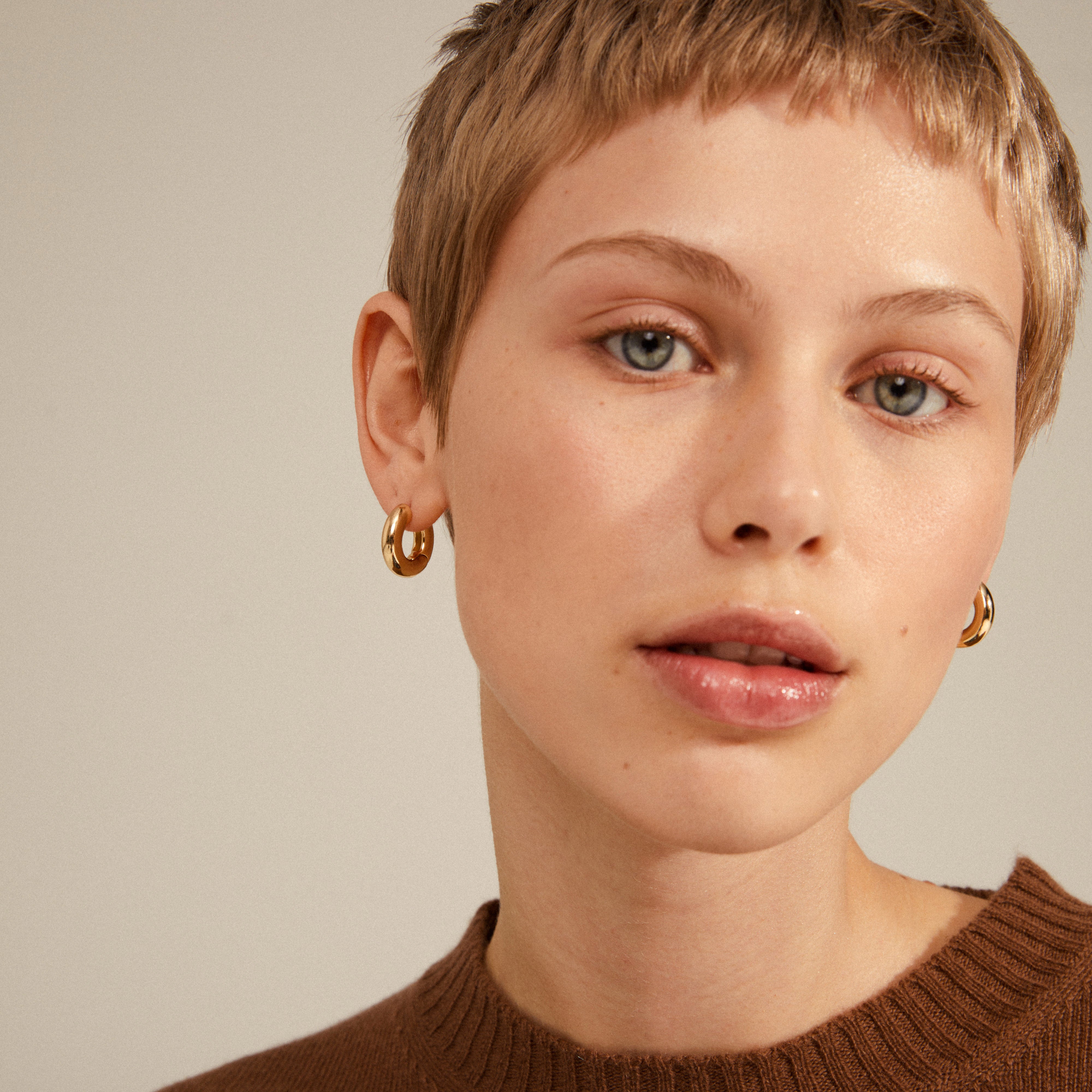 AICA chunky hoop earrings gold-plated, worn by a woman with short blonde hair, showcasing their timeless design and chunky silhouette from Pilgrim.