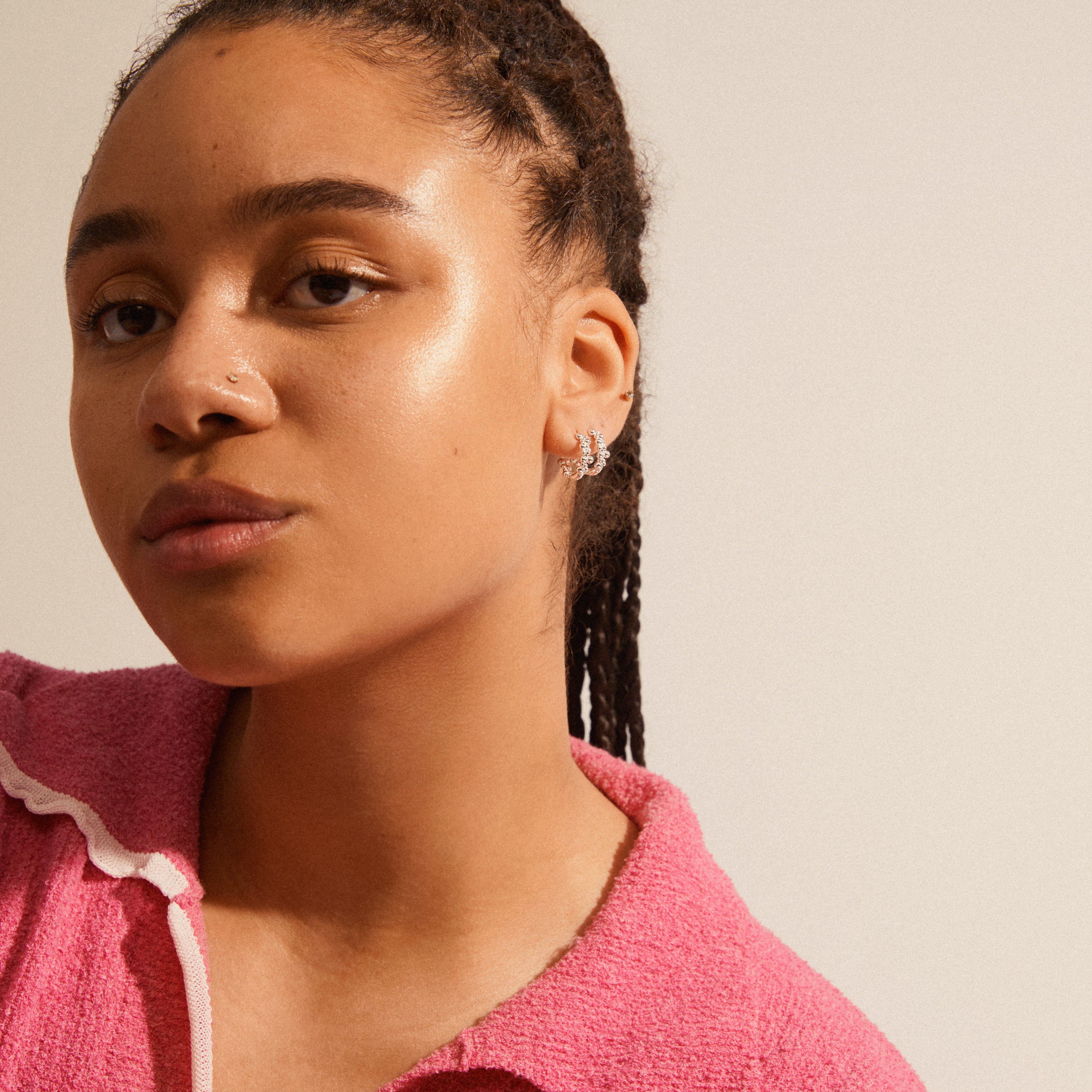 Woman with braided hair wearing SOLIDARITY medium bubbles hoops, silver-plated earrings, featuring playful asymmetric bubble design for a modern, stylish look.