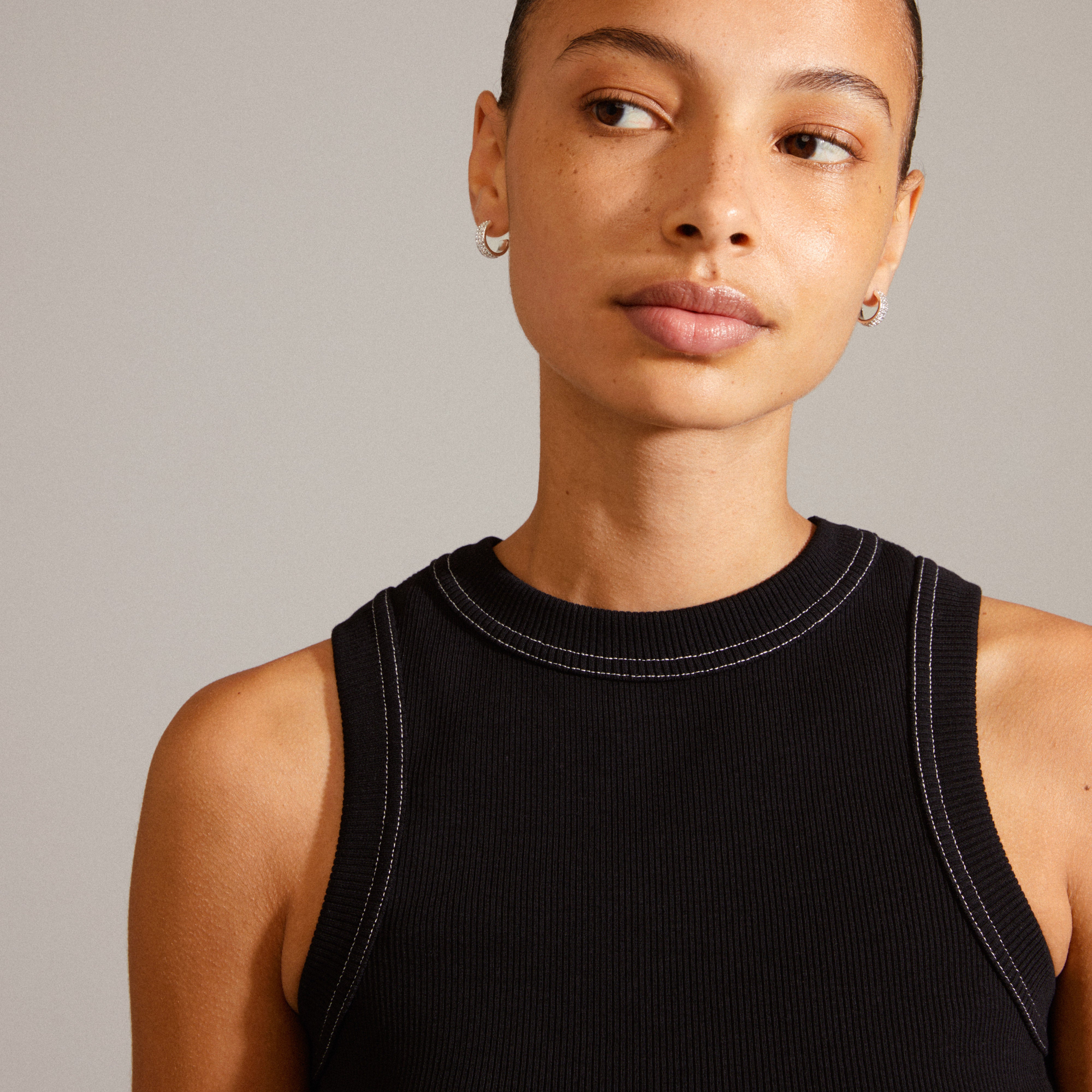 MATYLDA crystal hoop earrings, silver-plated, shown worn by a woman in a black tank top, highlighting their chunky silhouette and sparkling Preciosa crystals.