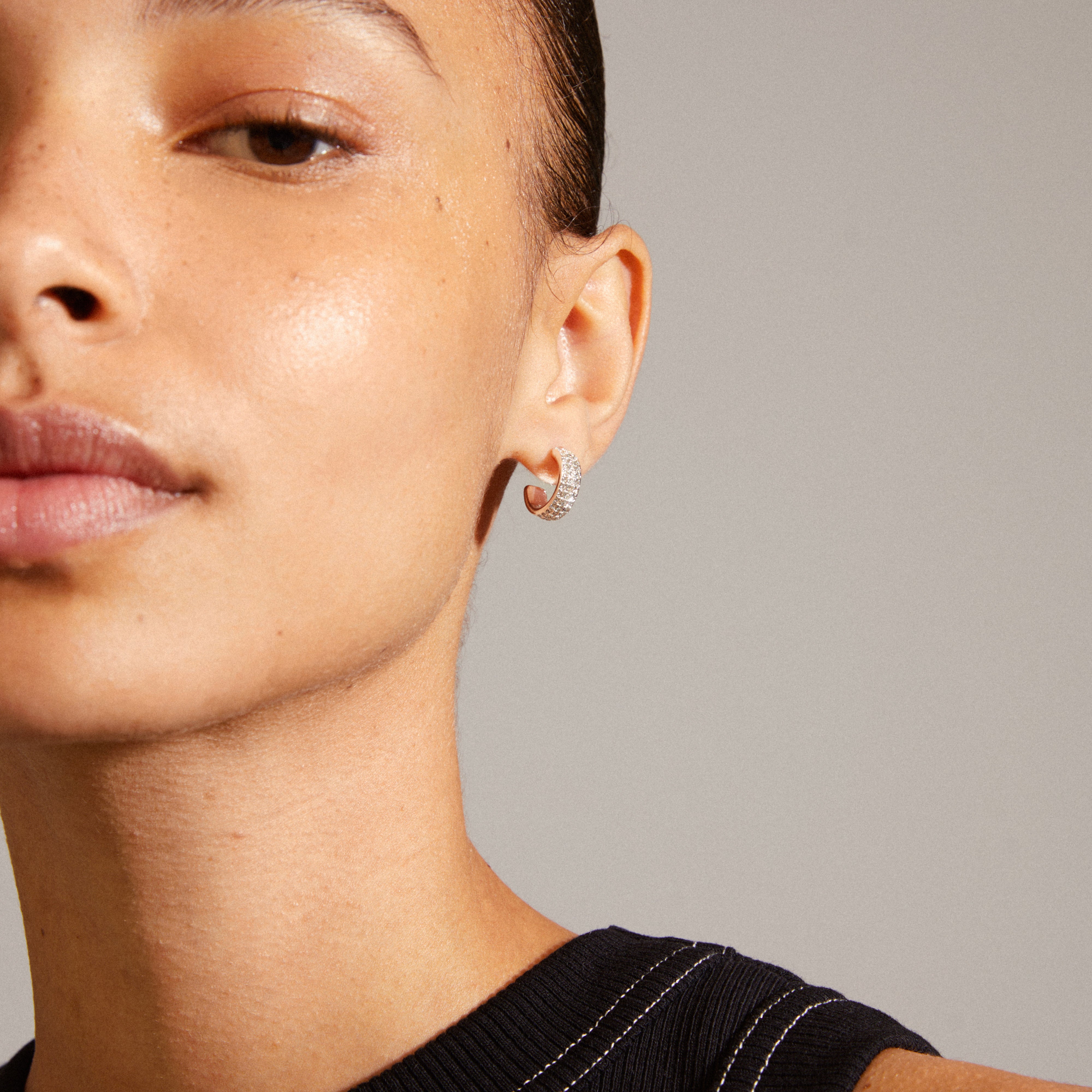 Close-up of a woman's ear showcasing MATYLDA silver-plated crystal hoop earrings from Pilgrim, highlighting their chunky silhouette and sparkling Preciosa crystals.