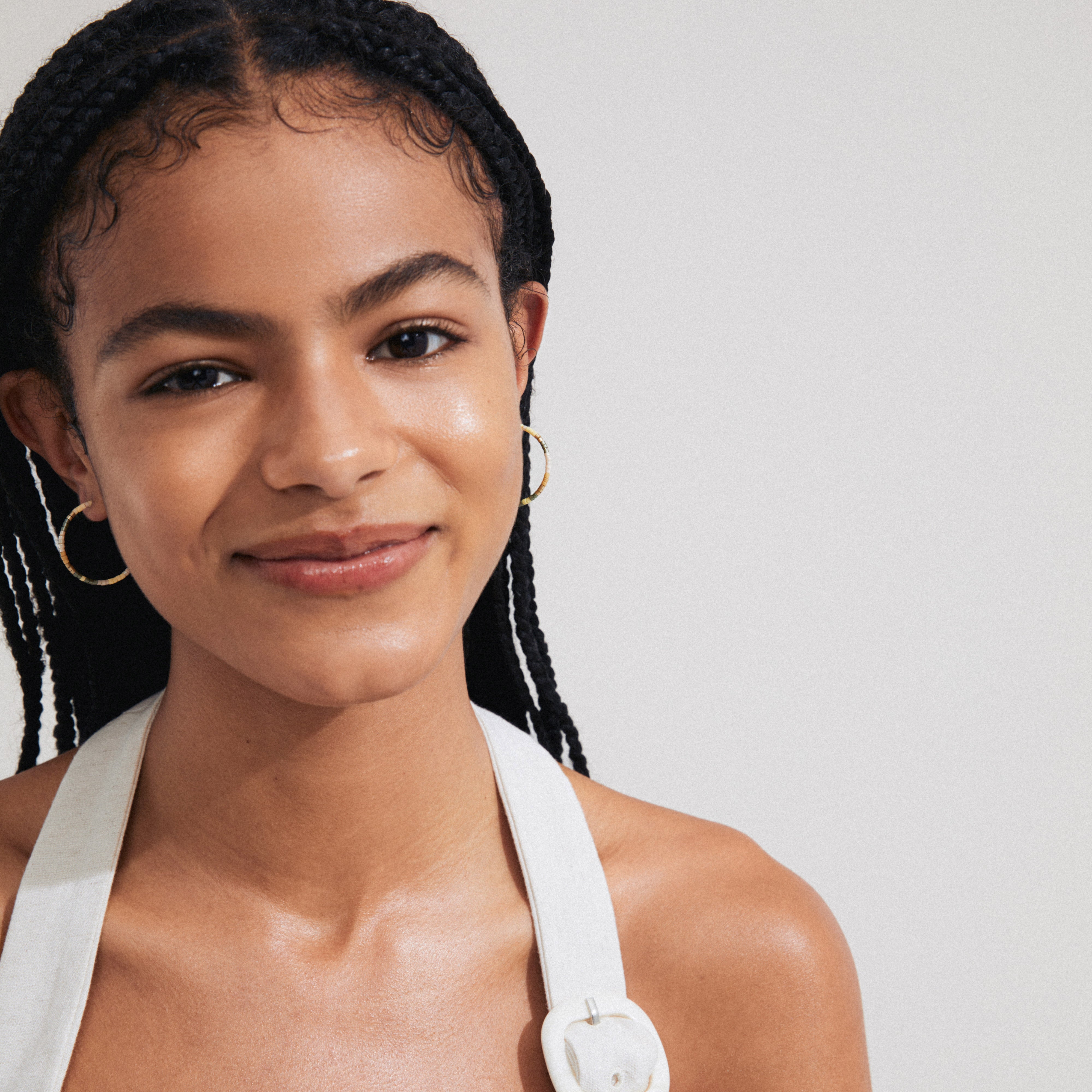 Woman wearing Pilgrim's ALISON gold-plated hoop earrings with earthy glass beads, showcasing a natural bohemian style, smiling directly at the camera.