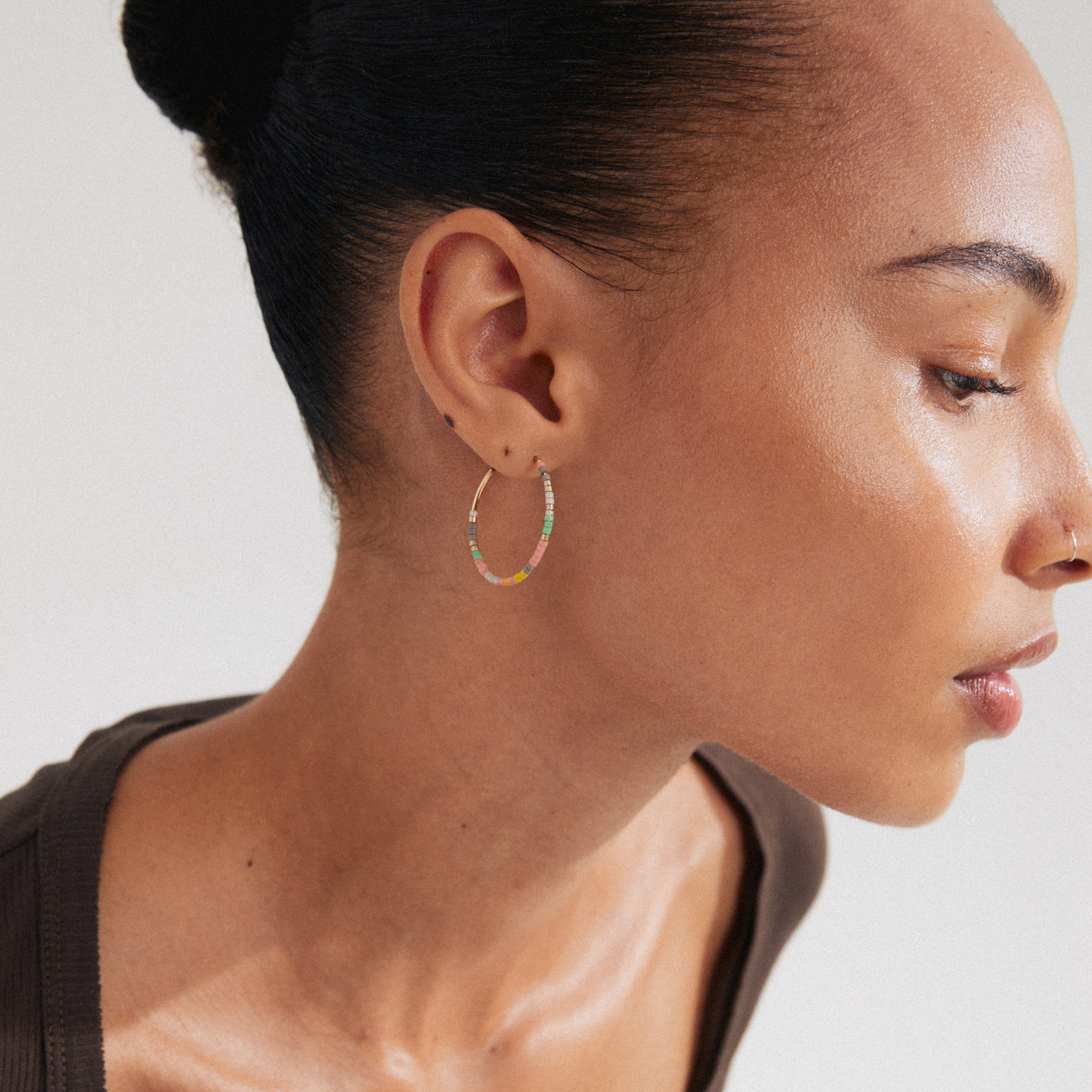 ALISON hoop earrings rose/gold-plated, featuring pink and yellow glass beads, adorn a woman's ear, showcasing a luxurious boho style from Pilgrim's collection.